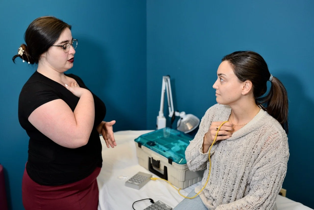 An acupuncturist performs SAAT treatment on female patient in blue treatment room.