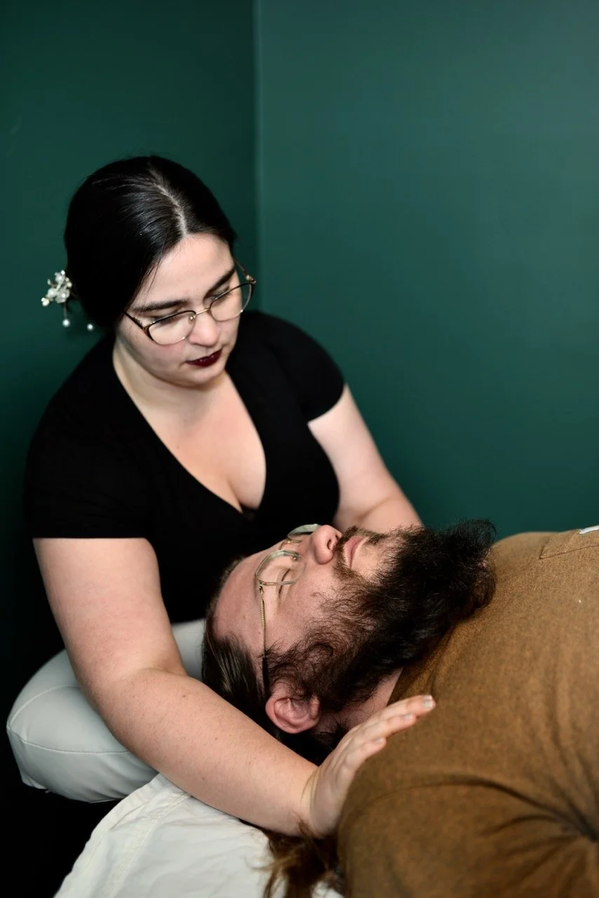 A woman providing support or therapy to a man lying down with eyes closed.