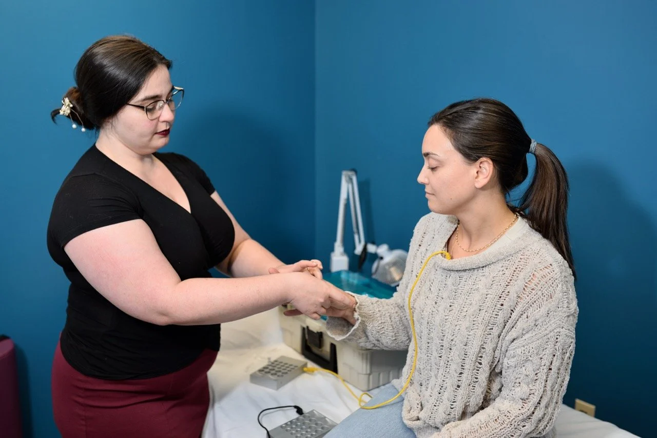 An acupuncturist performs SAAT treatment on female patient in blue treatment room.