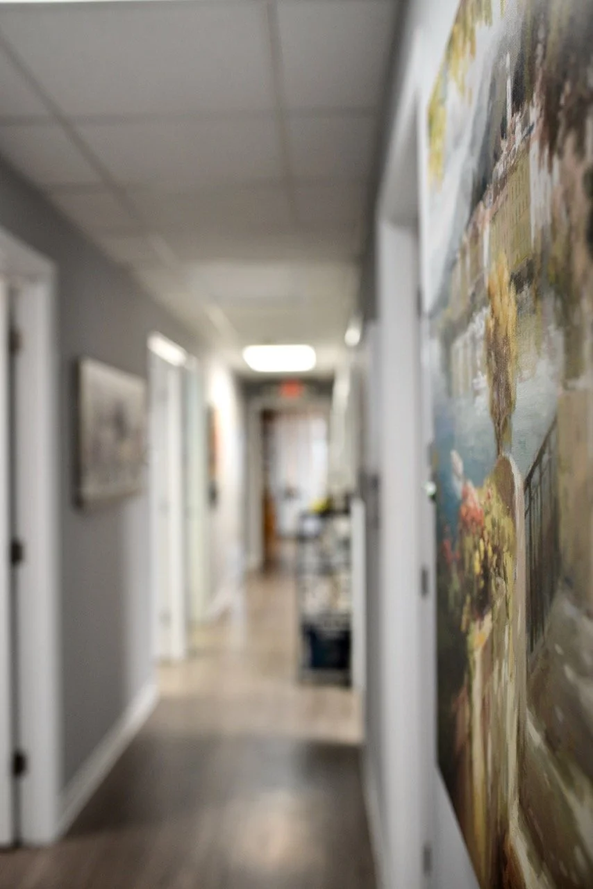 Blurred hallway with paintings on the walls and a door at the far end.