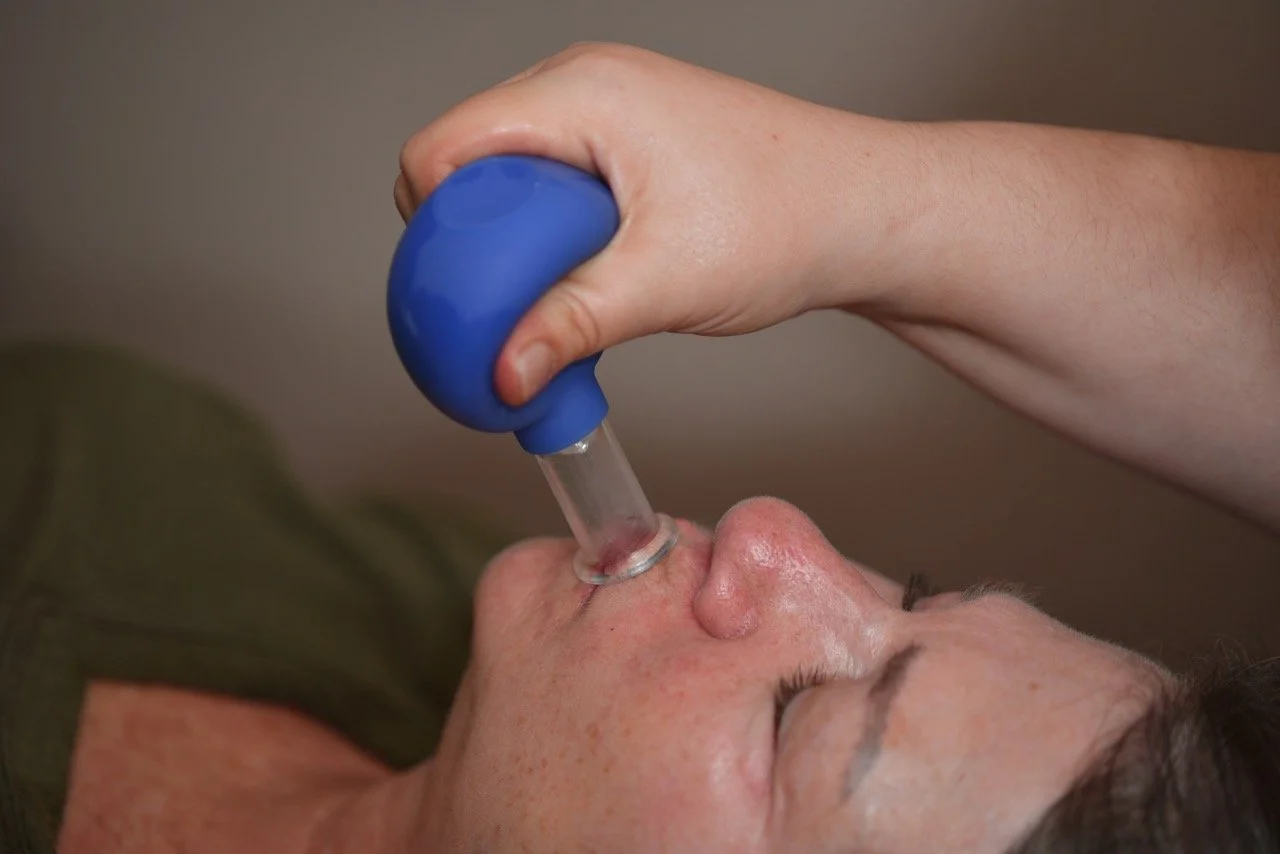 Person using a vaporizer on their face, with the tip pressed against the nose.