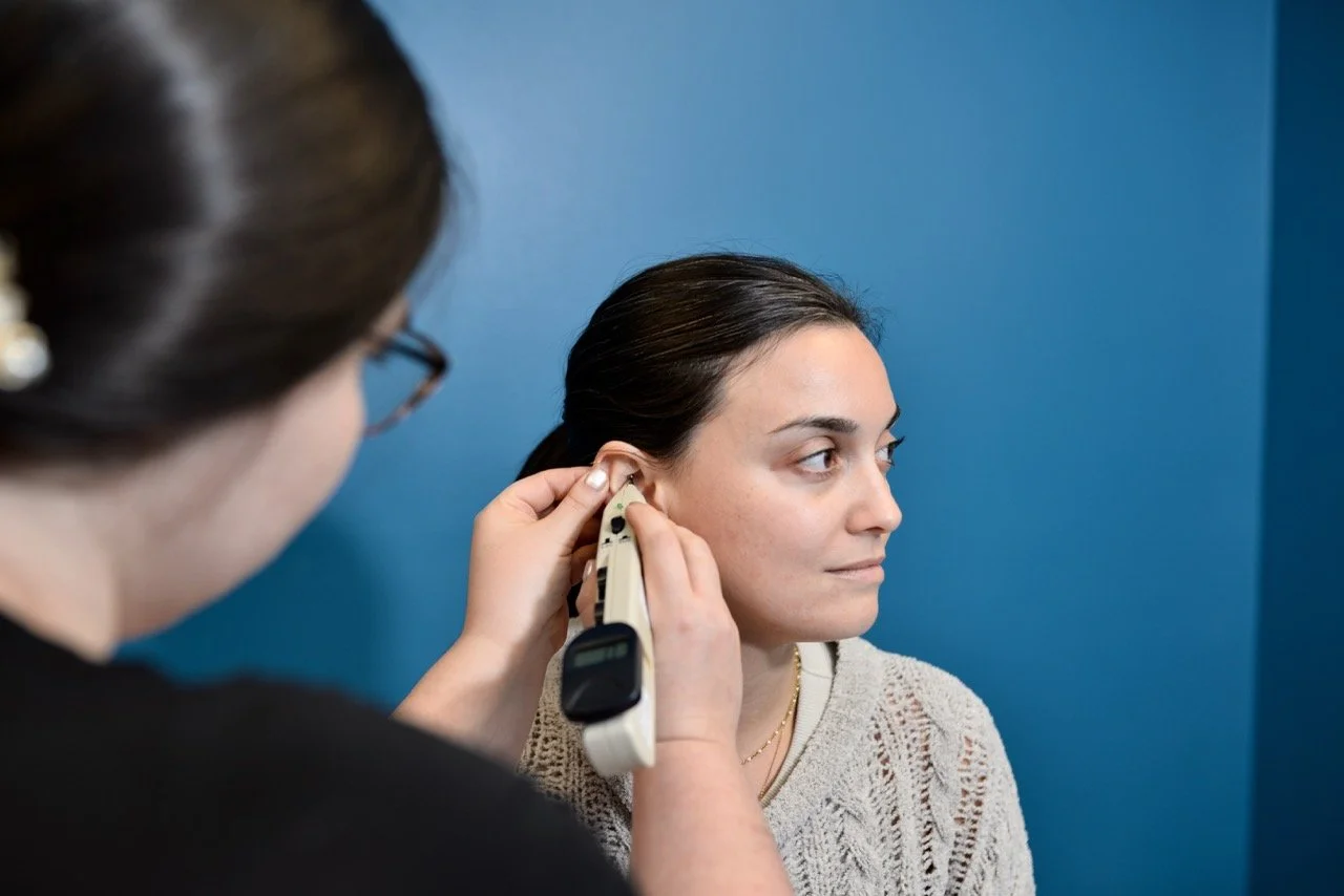 A woman has her ear examined by an acupuncturist performing SAAT treatment.