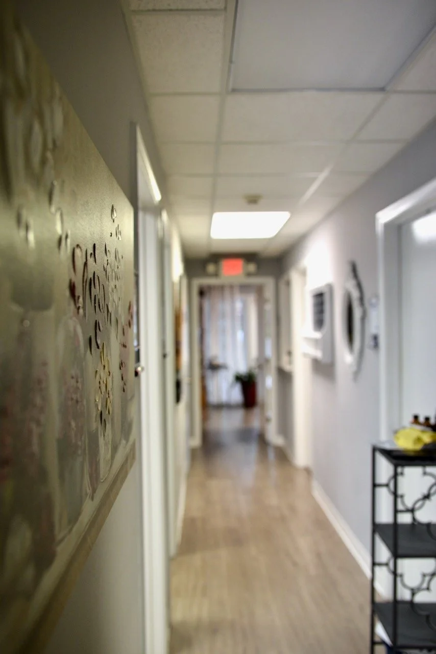 Blurred hallway with a door at the end, a plant in a pot, and decorations on the walls.