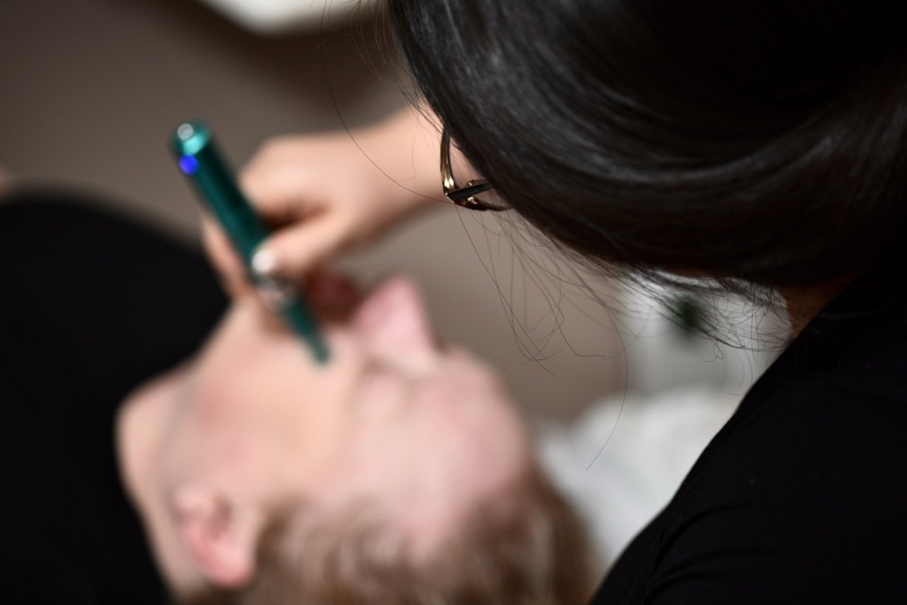 A professional acupuncturist performing micro needling for smoother skin on a woman's face.