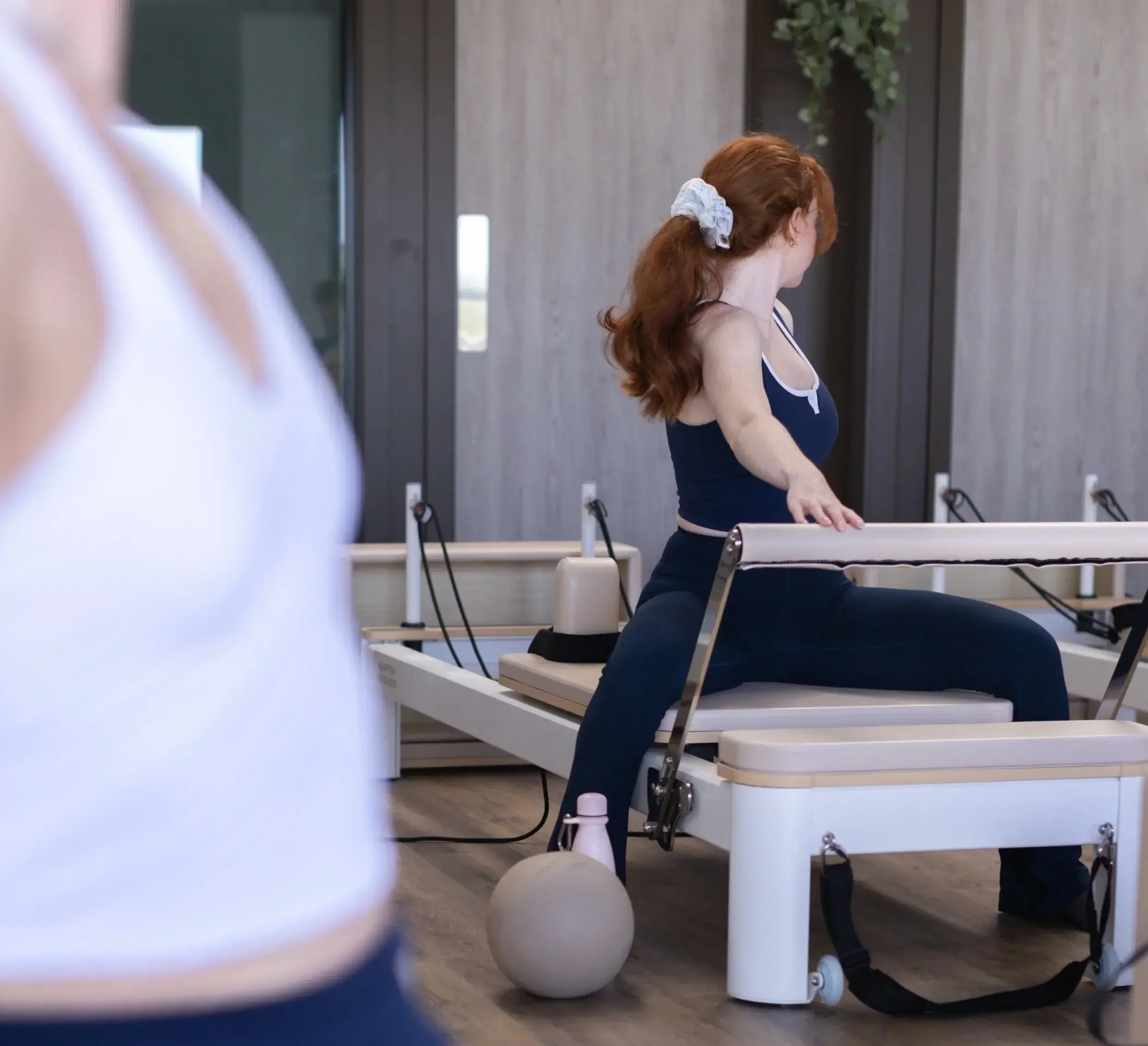 Woman doing a seated side stretch on a reformer