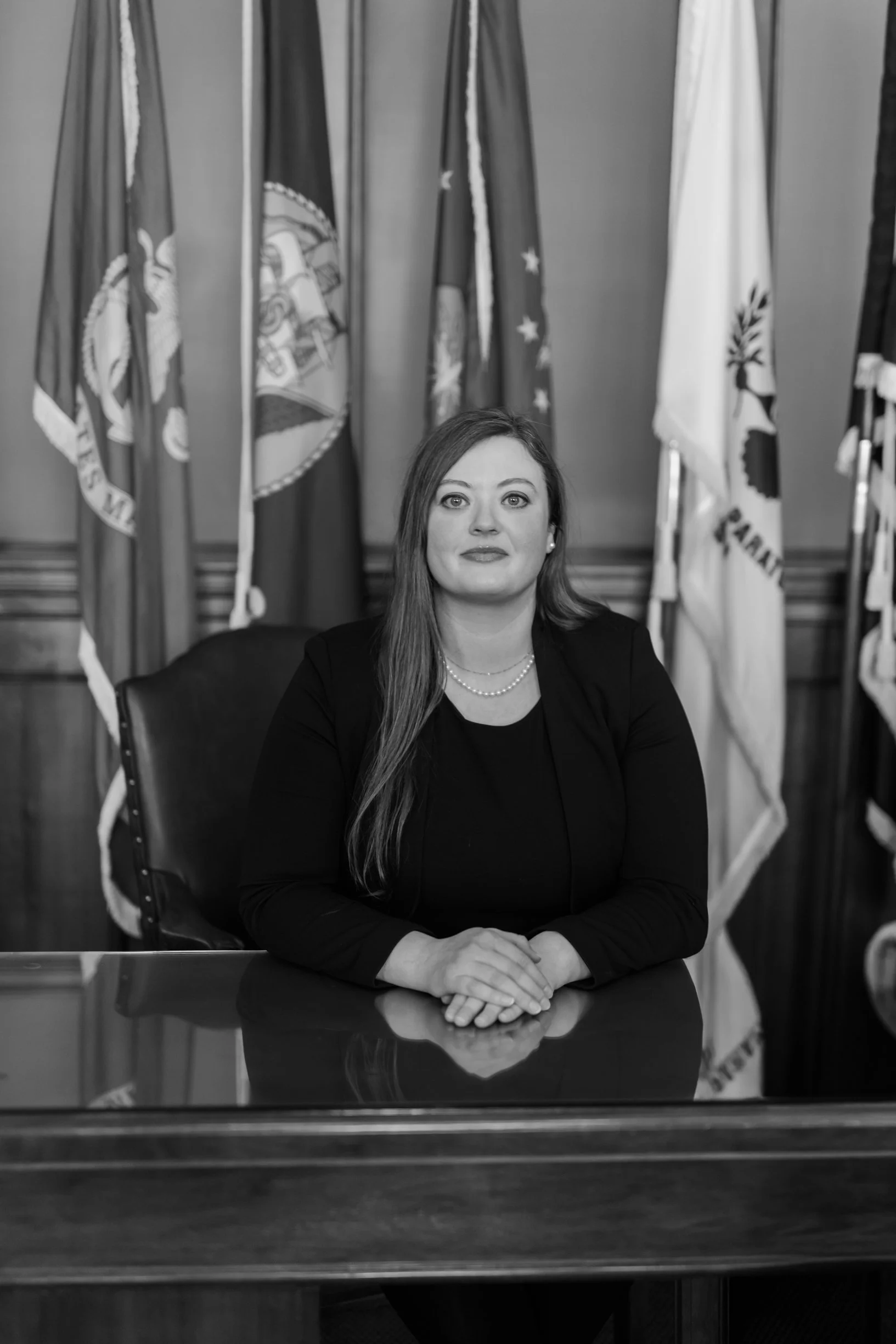 photo of a lady sat in a room with flags in the background