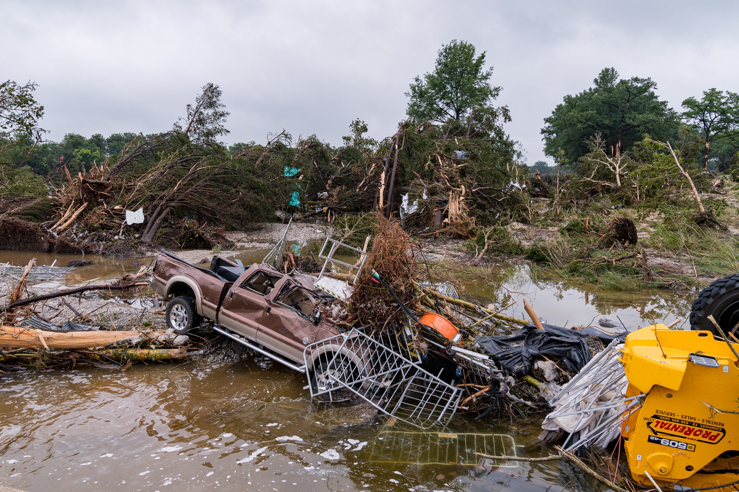 Flood debris including a stranded pickup truck, twisted metal and uprooted trees lies piled along the Guadalupe River after catastrophic flash flooding in Kerrville, Texas.
