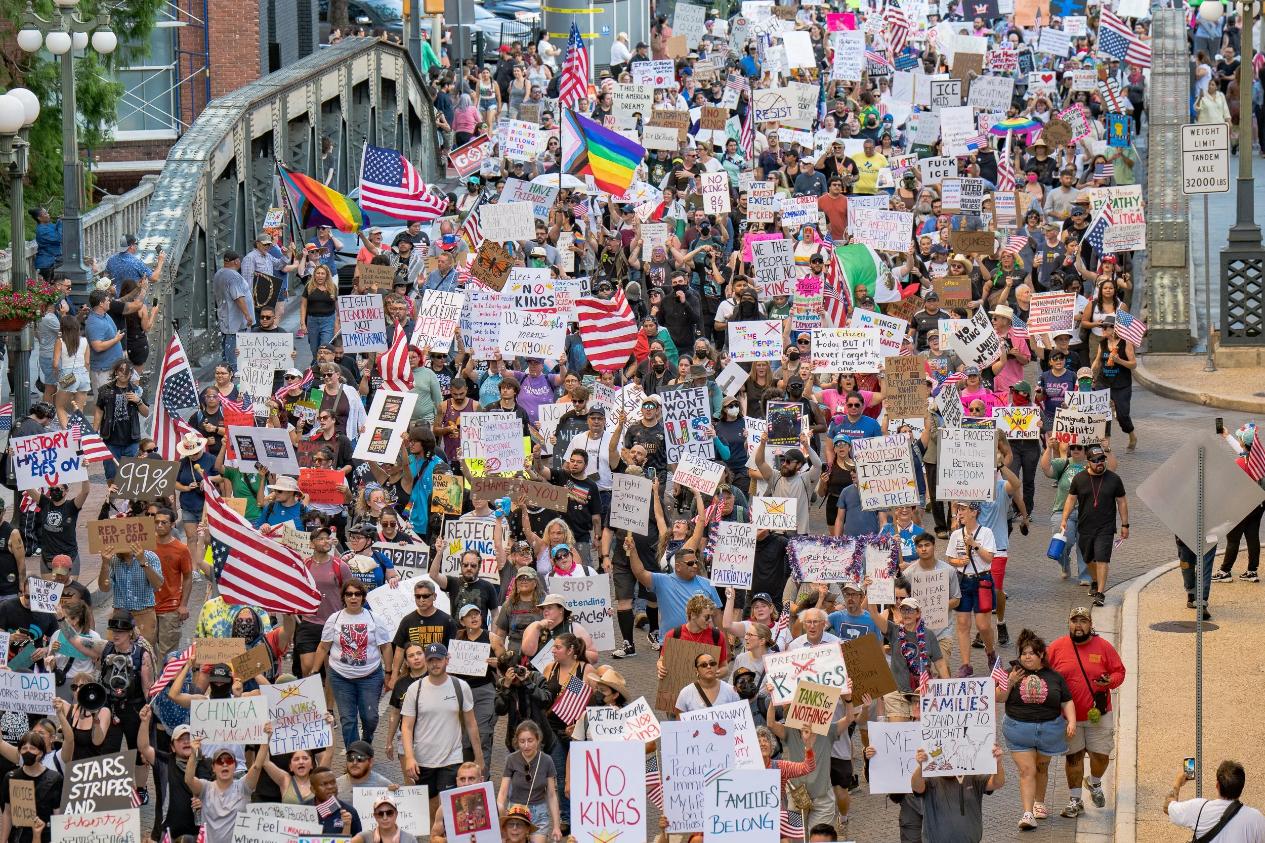 Thousands of protesters carrying signs and American flags fill Navarro Street in downtown San Antonio during the June 2025 “No Kings” immigration policy rally