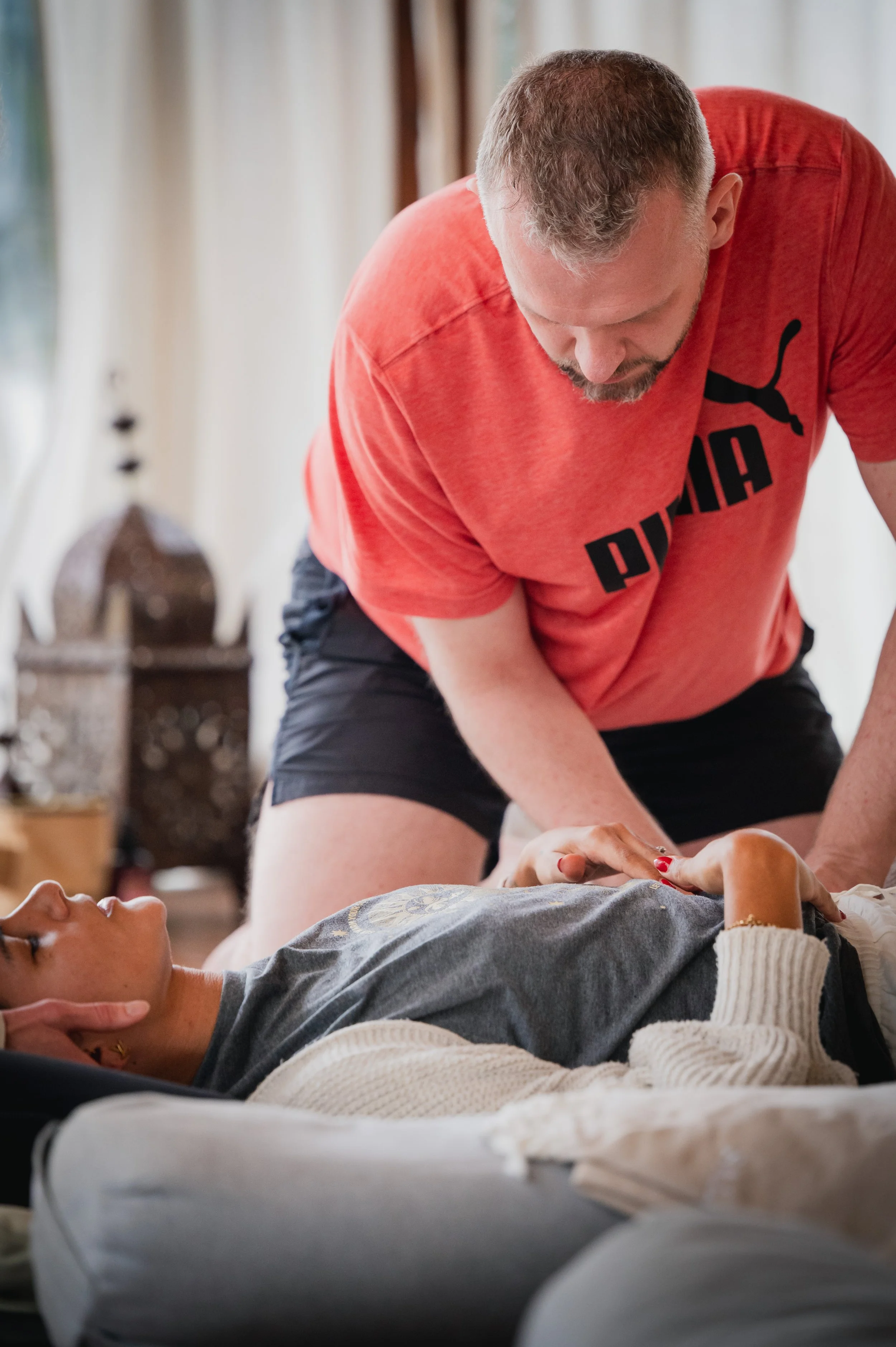 A man providing first aid or CPR to a woman lying on a couch in a home setting.