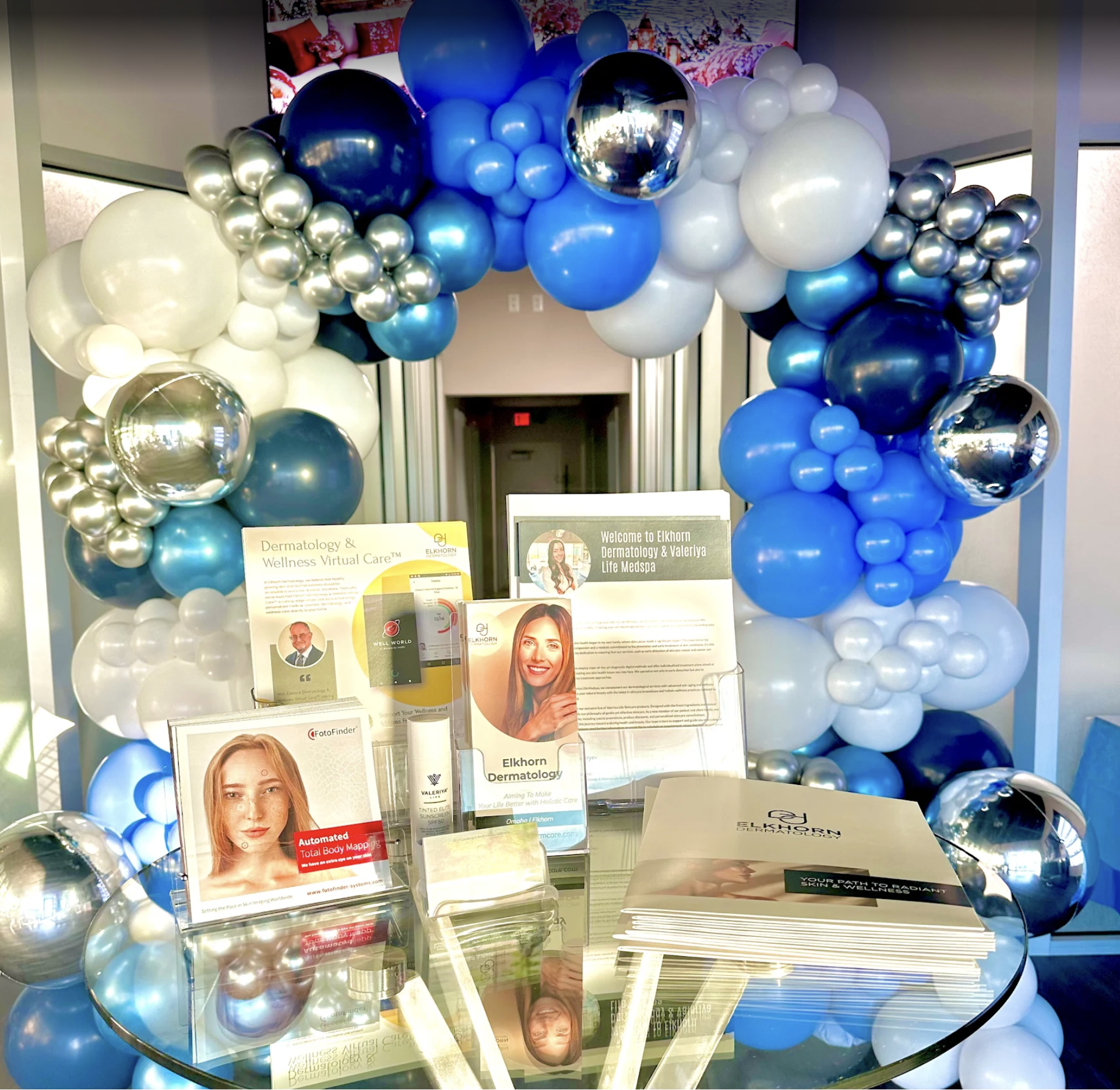 Corporate dermatologic product display event in Omaha featuring a balloon arch in blue, white, and silver for product launch and professional event decor.
