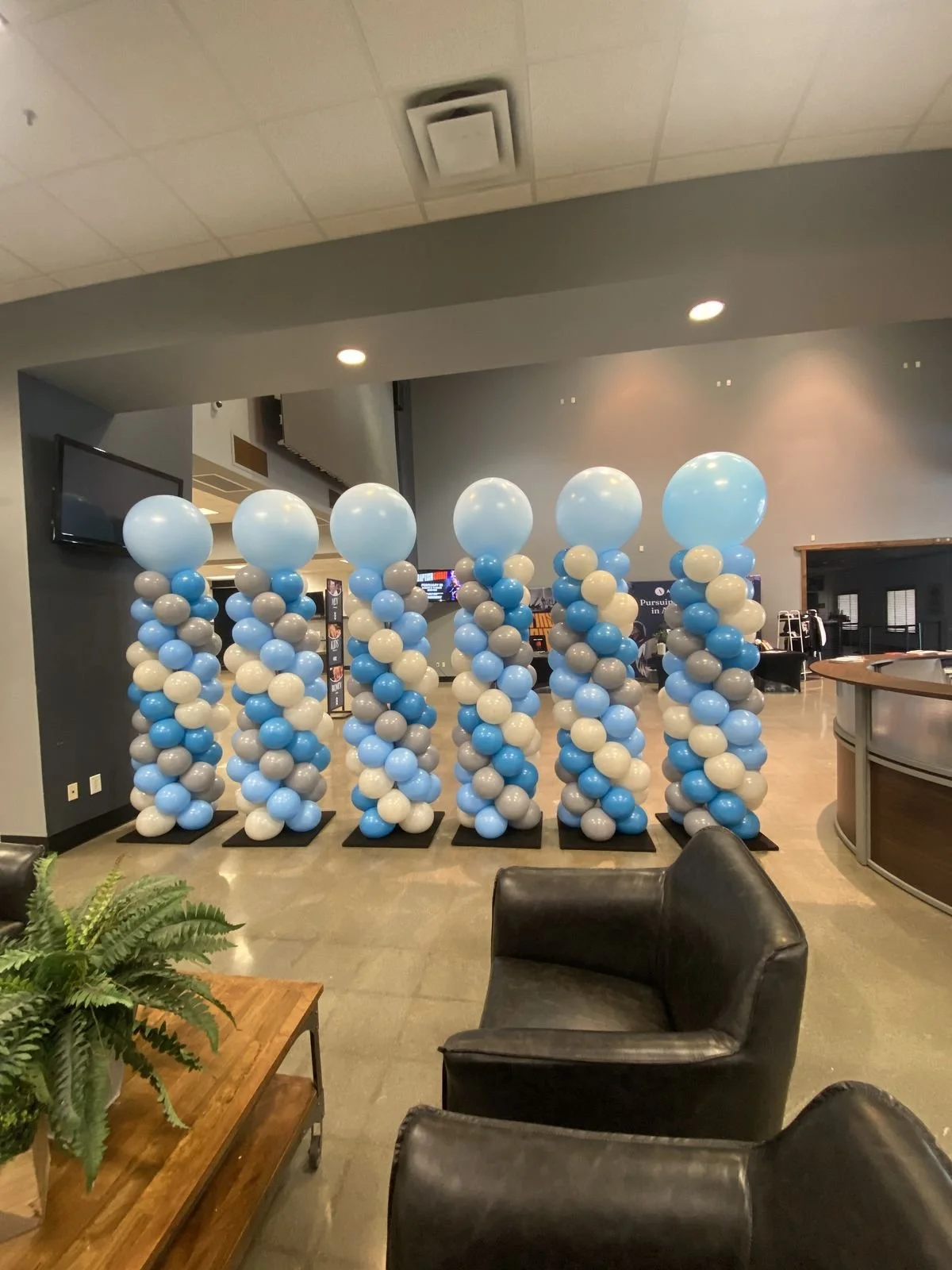 Corporate event balloon column installation in Omaha featuring baby blue, light grey, and white balloons for business event decor and entrance setup.