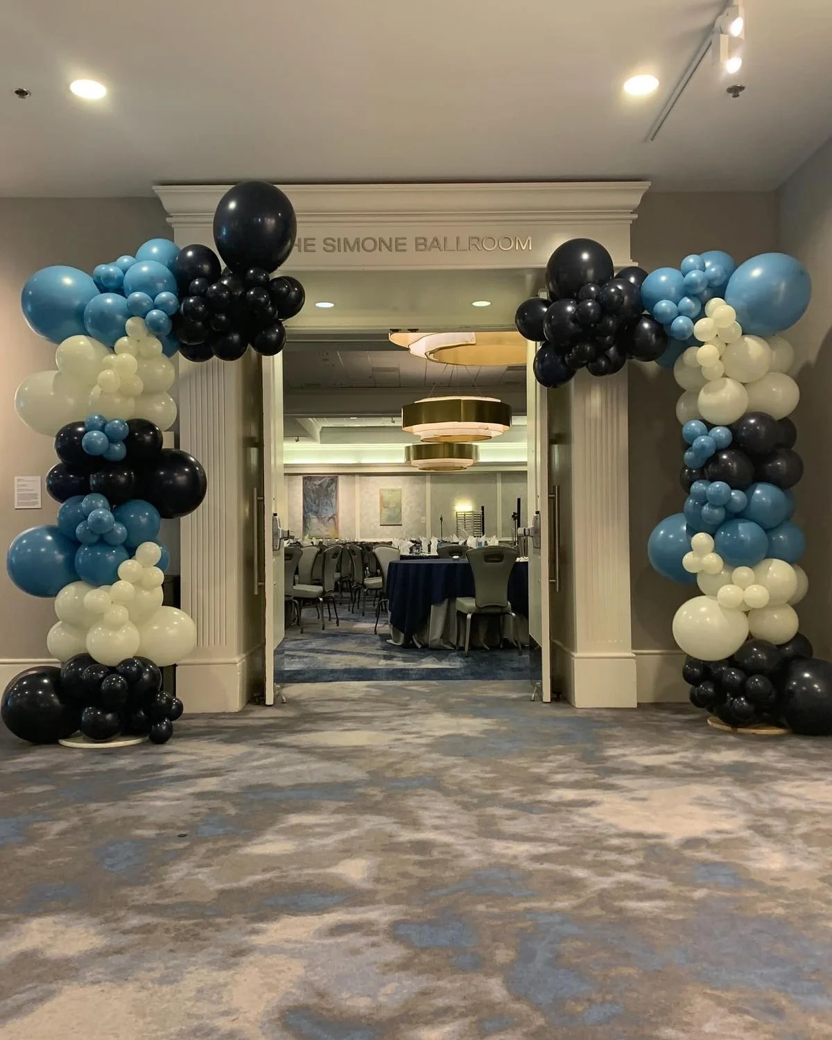 Grand opening balloon garland installation in Omaha with two organic balloon garlands at ballroom entrance in black, blue, and white for professional event decor.