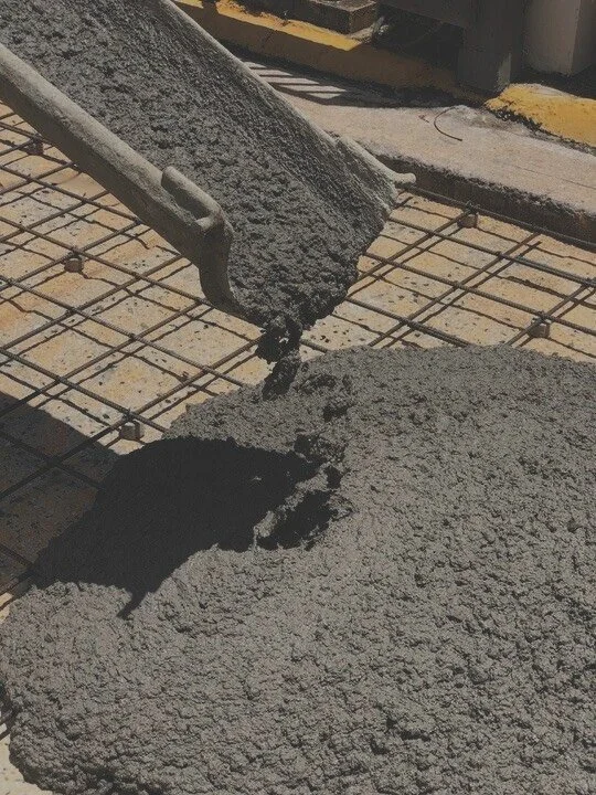 Wet concrete being poured onto a surface with a trowel visible.