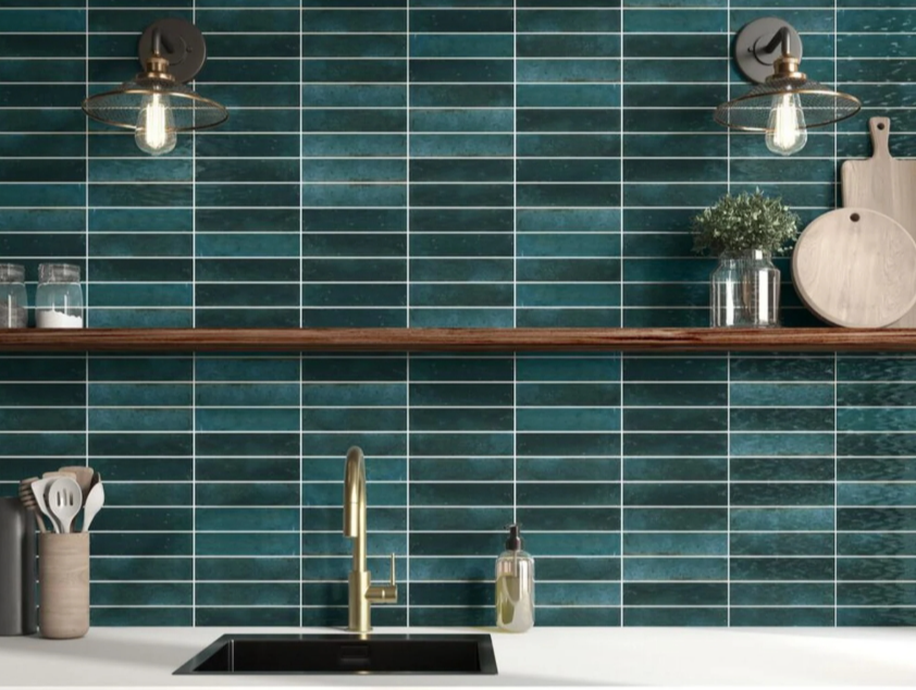 Modern kitchen with green subway tile backsplash, brass faucet, wooden shelf, glass jars, and kitchen accessories.