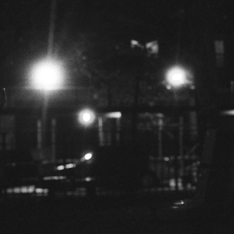 A black and white photo of a Brooklyn, NY street. The style is black and white, grainy, and mysterious.