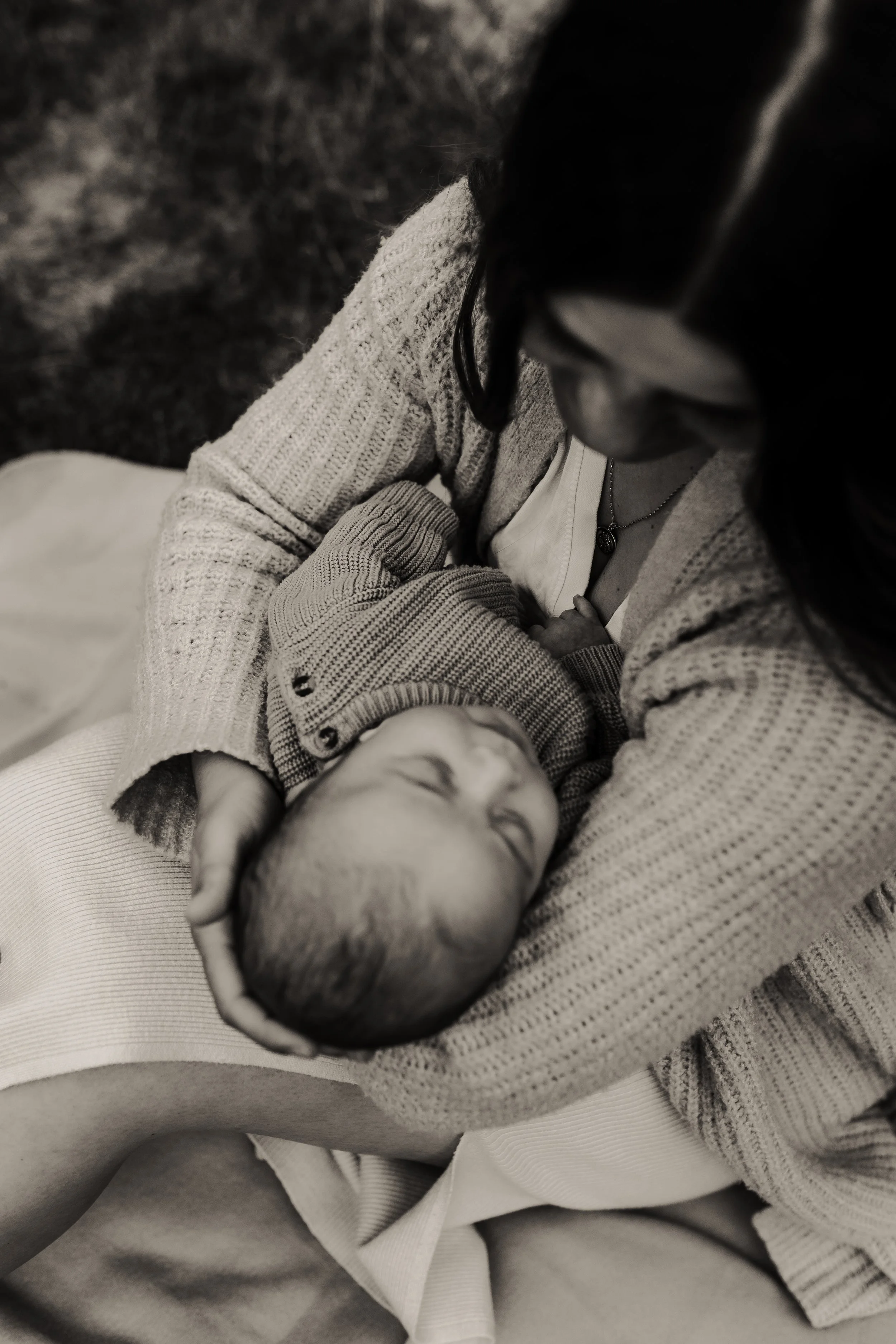 Eine Frau hält ein schlafendes Baby in den Armen, in Schwarz-Weiß-Fotografie.