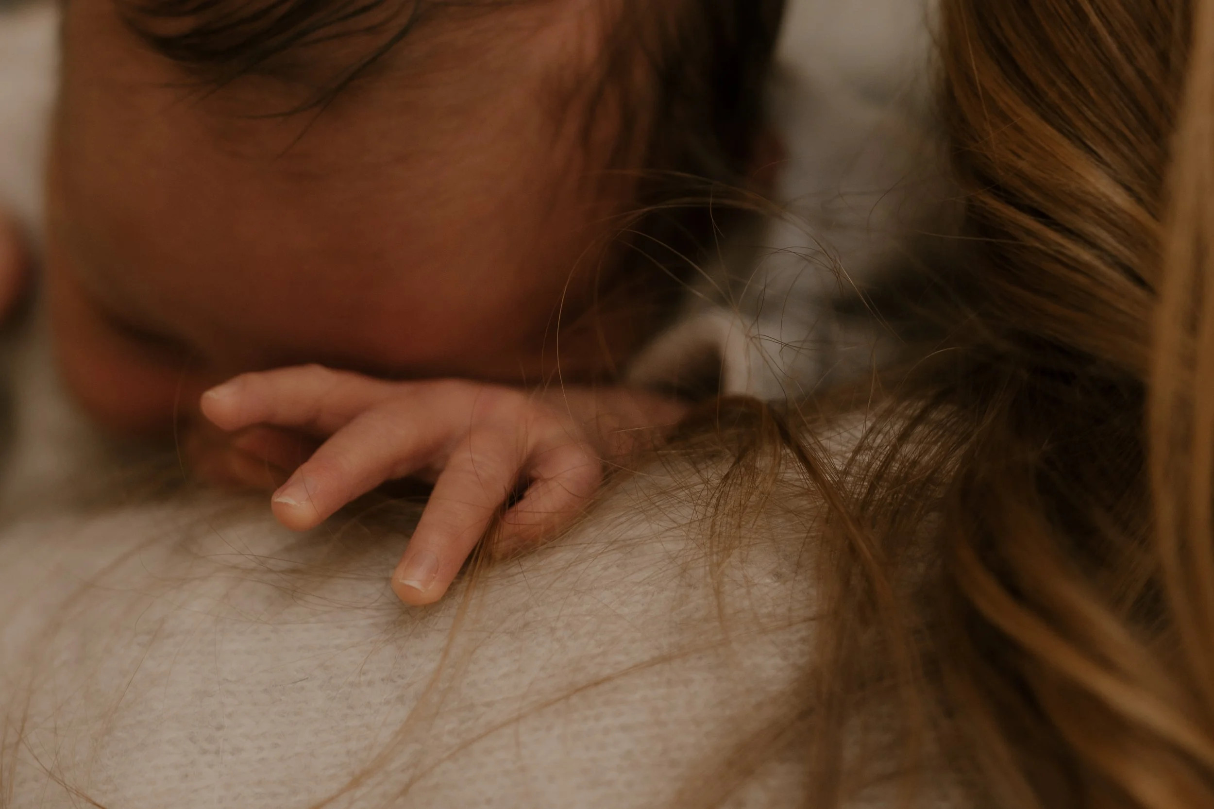 Nahaufnahme einer Person mit roten Haaren, die den Kopf auf die Schulter einer anderen Person legt, deren langes Haar sichtbar ist.