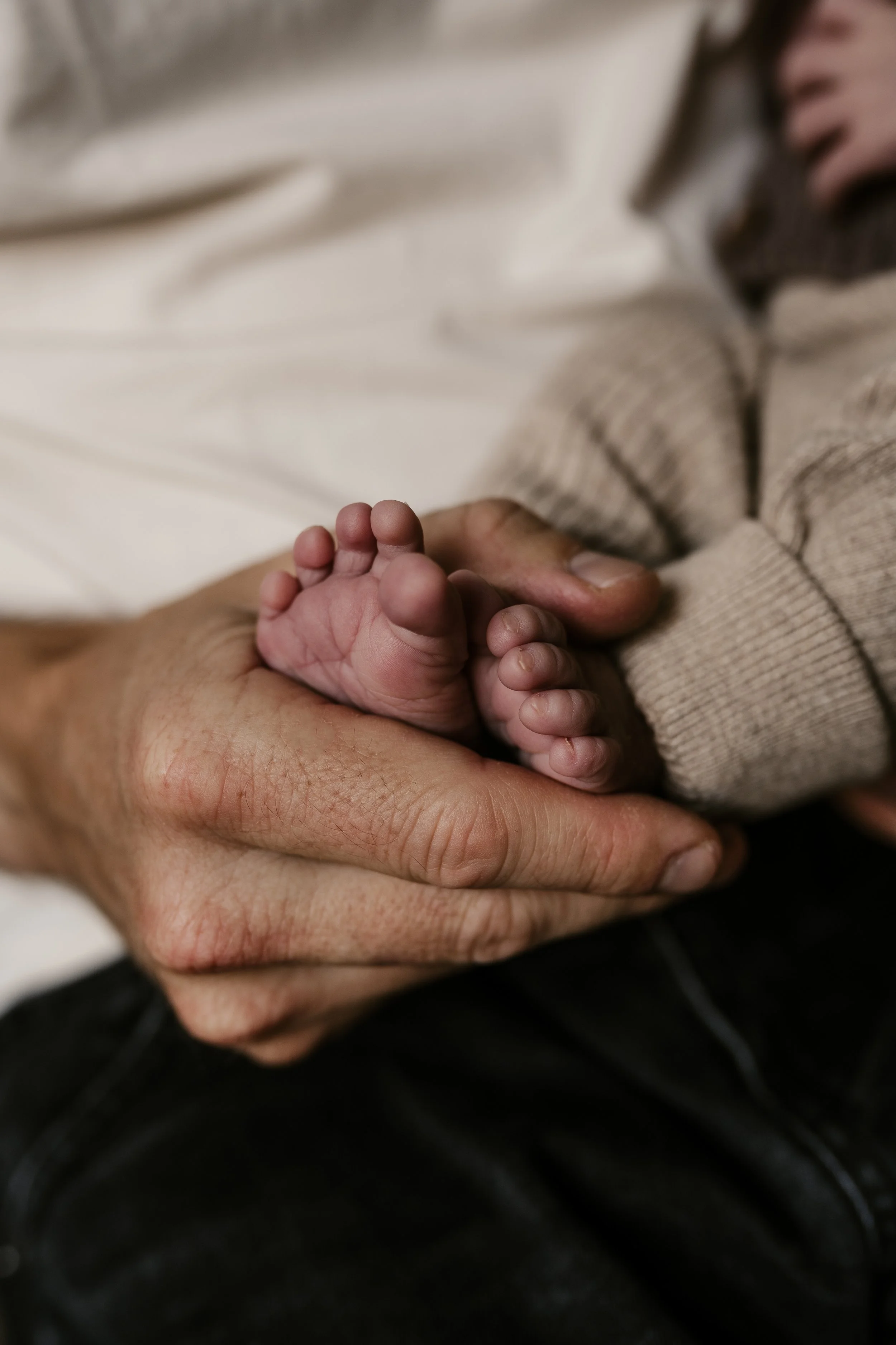 Nahaufnahme eines Menschen, der die winzigen Füße eines Babys hält.