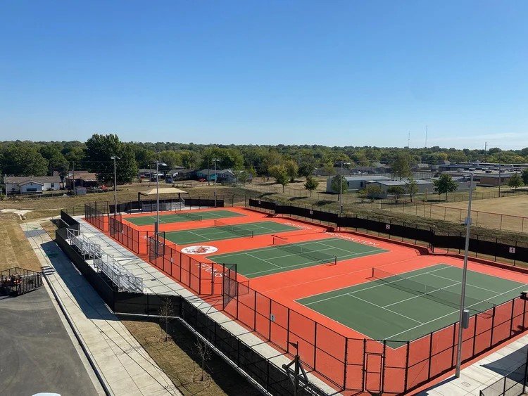 Chain link fencing around outdoor tennis courts.