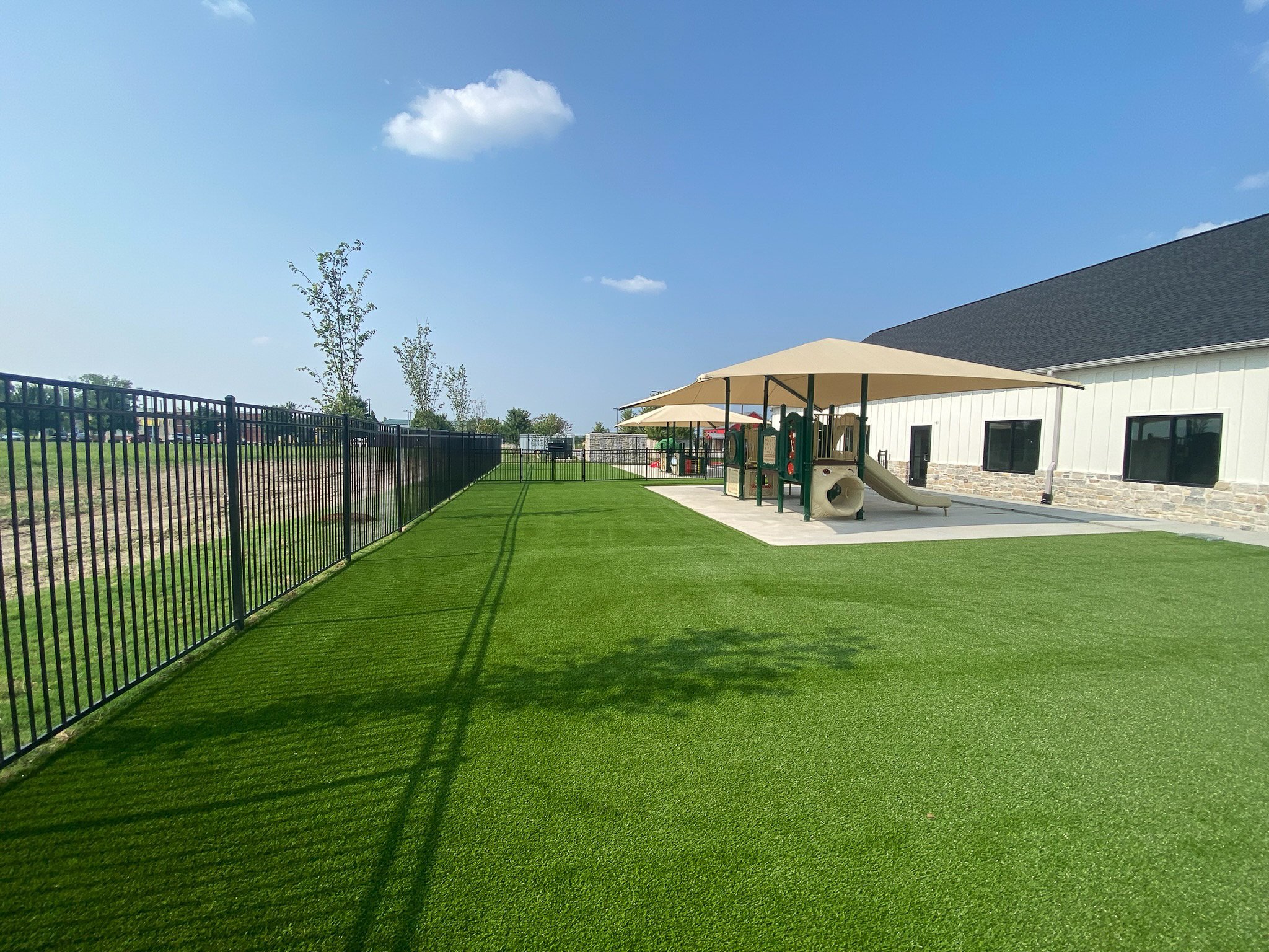 Black metal fence along an artificial turf play area at a commercial property