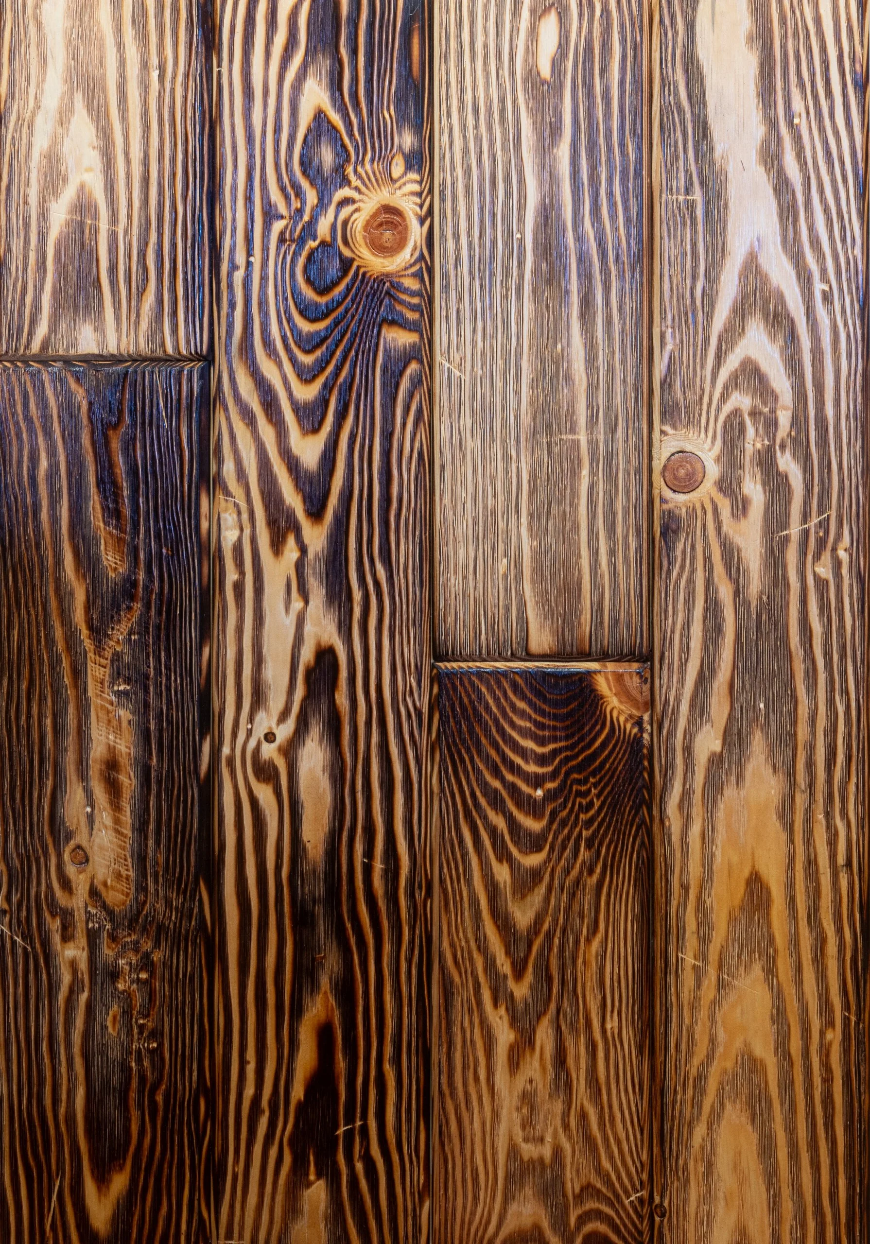 Close-up of wooden planks with visible grain and knots, showing a stained or burnt pattern on the wood surface.