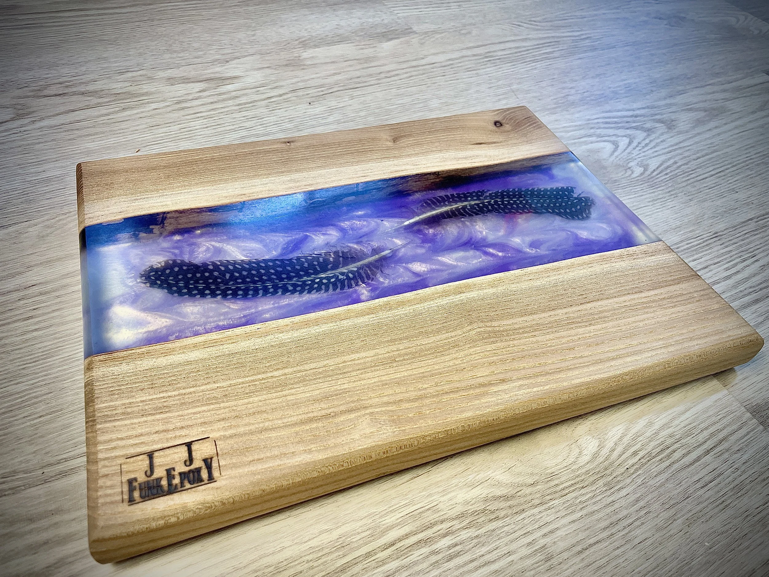 Wooden box with a glass inlay containing two decorative feathers, placed on a light wooden surface.