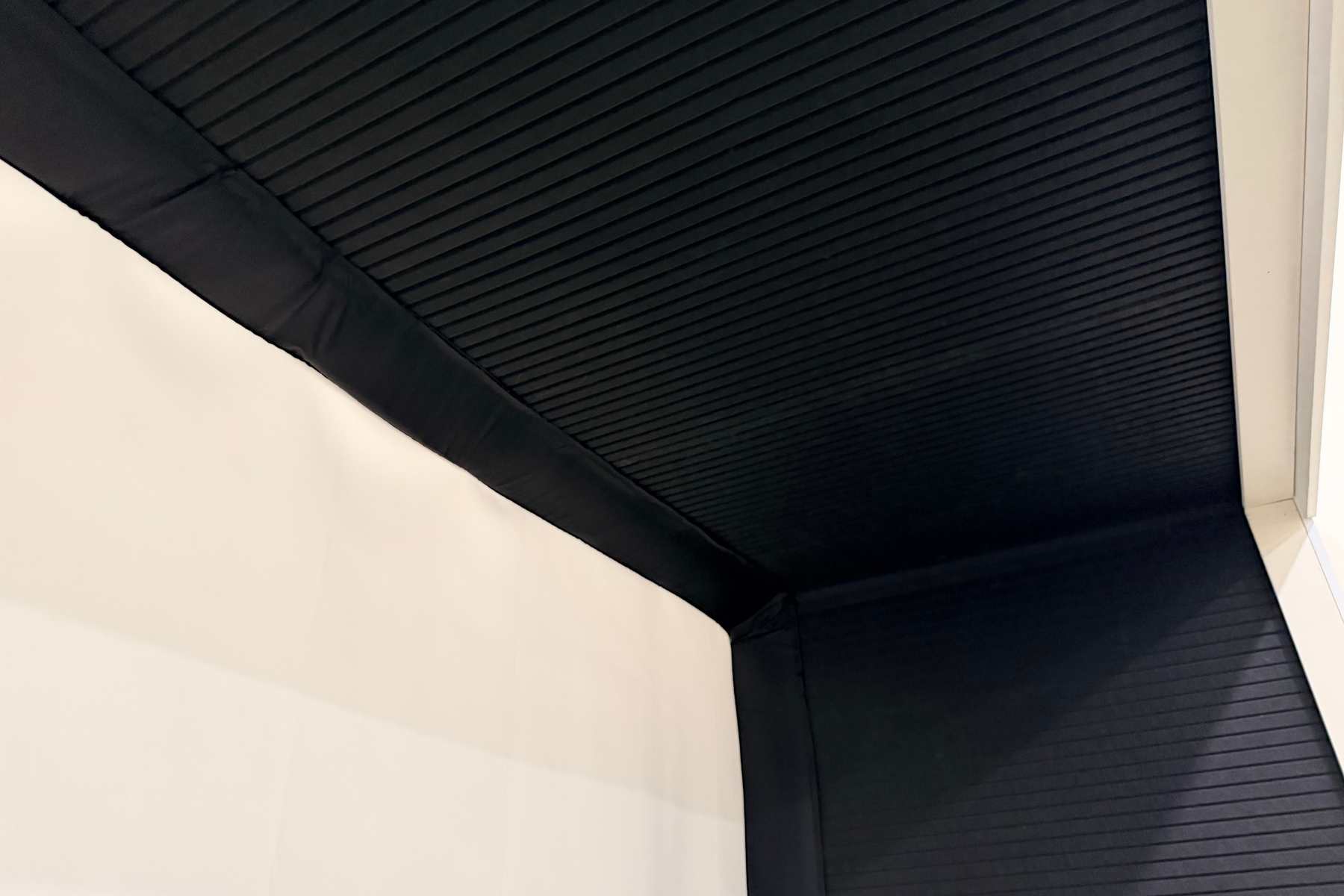 Close-up of the corner of a golf simulator with black slatted paneling.