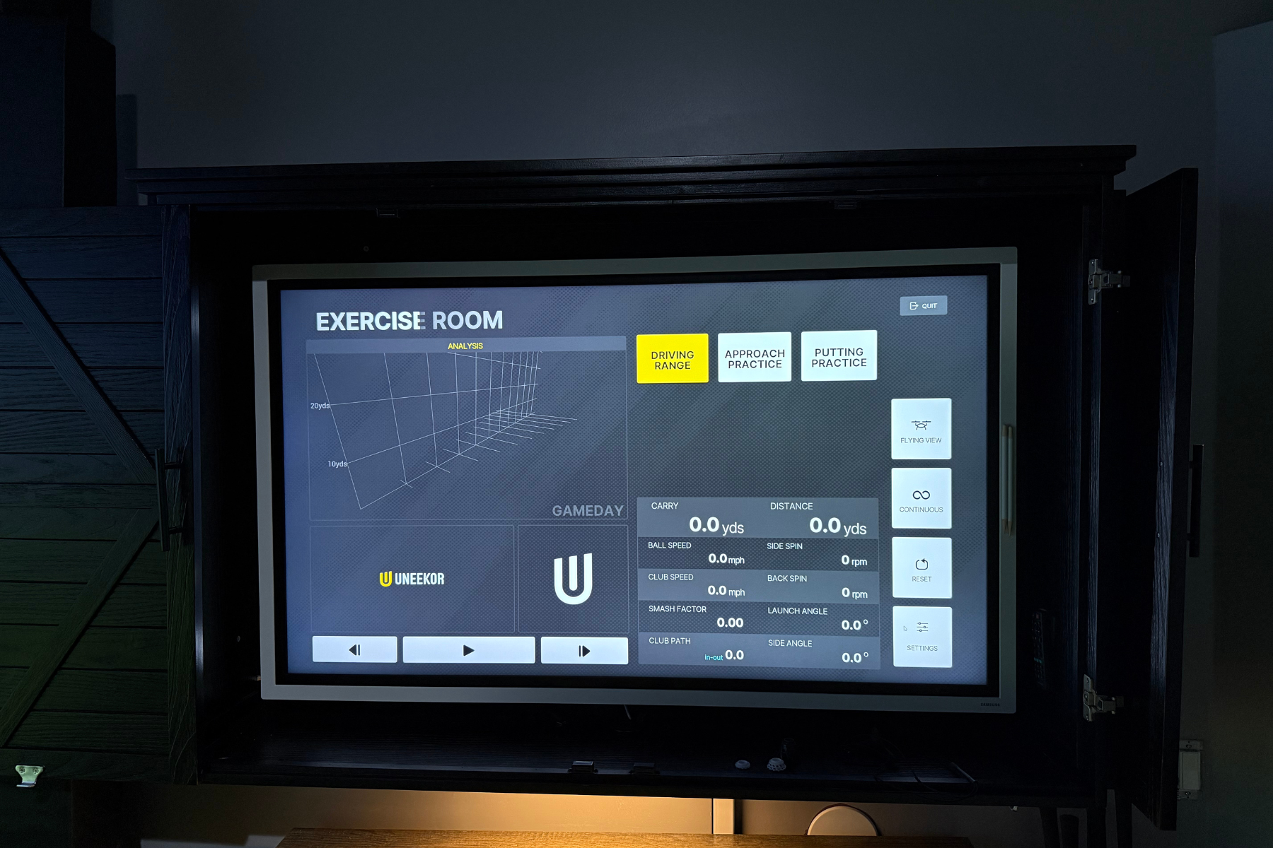 Digital screen in exercise room showing analysis and practice options for golf simulation with details like carry, distance, ball speed, and spin stats.