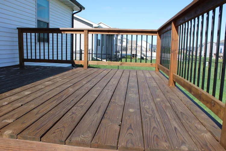 Brown-stained deck boards and railing with black balusters
