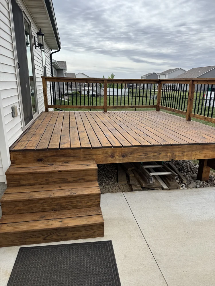 Wood deck and stairs with brown stain and black metal balusters