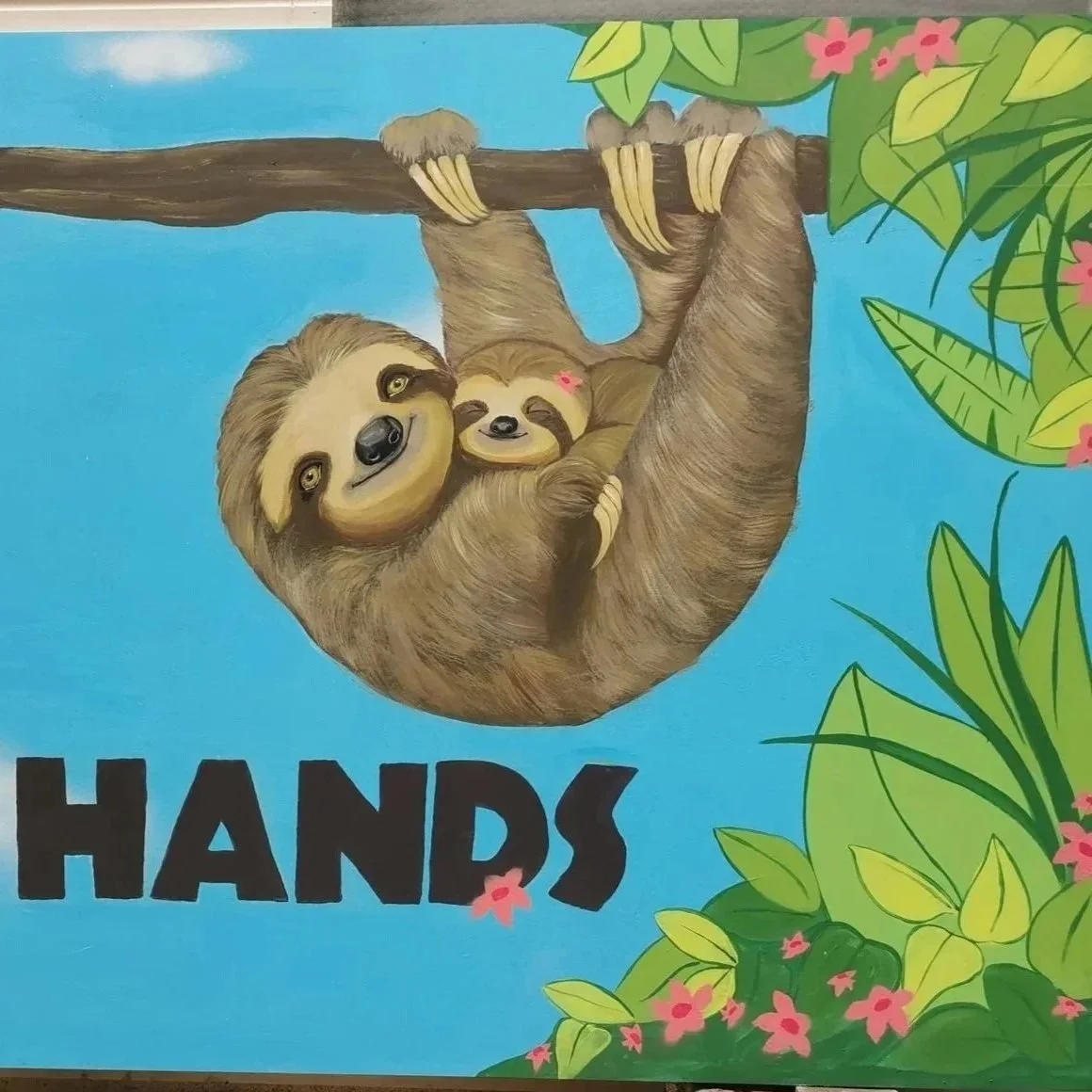 Kind Hands mural is one of four murals for a school playground. I used a sloth mom looking after her baby, cradling her with her paws (hands) I went for a jungle theme for these murals.