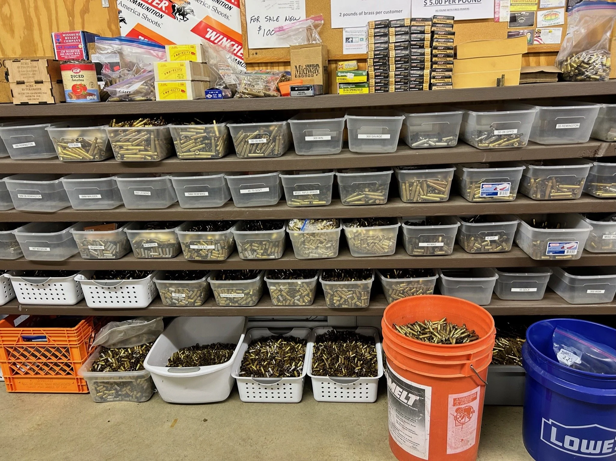 Shelves filled with bags and containers of brass ammunition cartridges in a sporting goods store.