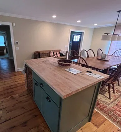Open-concept kitchen and dining area with a wooden island, blue cabinets, and a dining table with chairs.