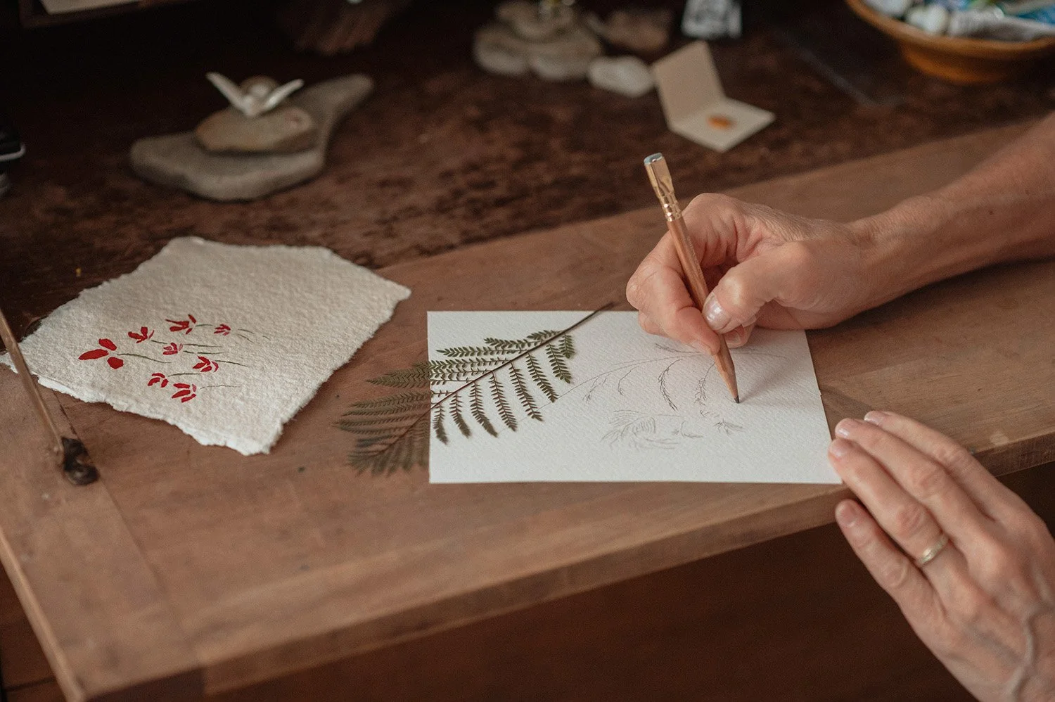 woman's hands drawing ferns on a fold out secretary desktop