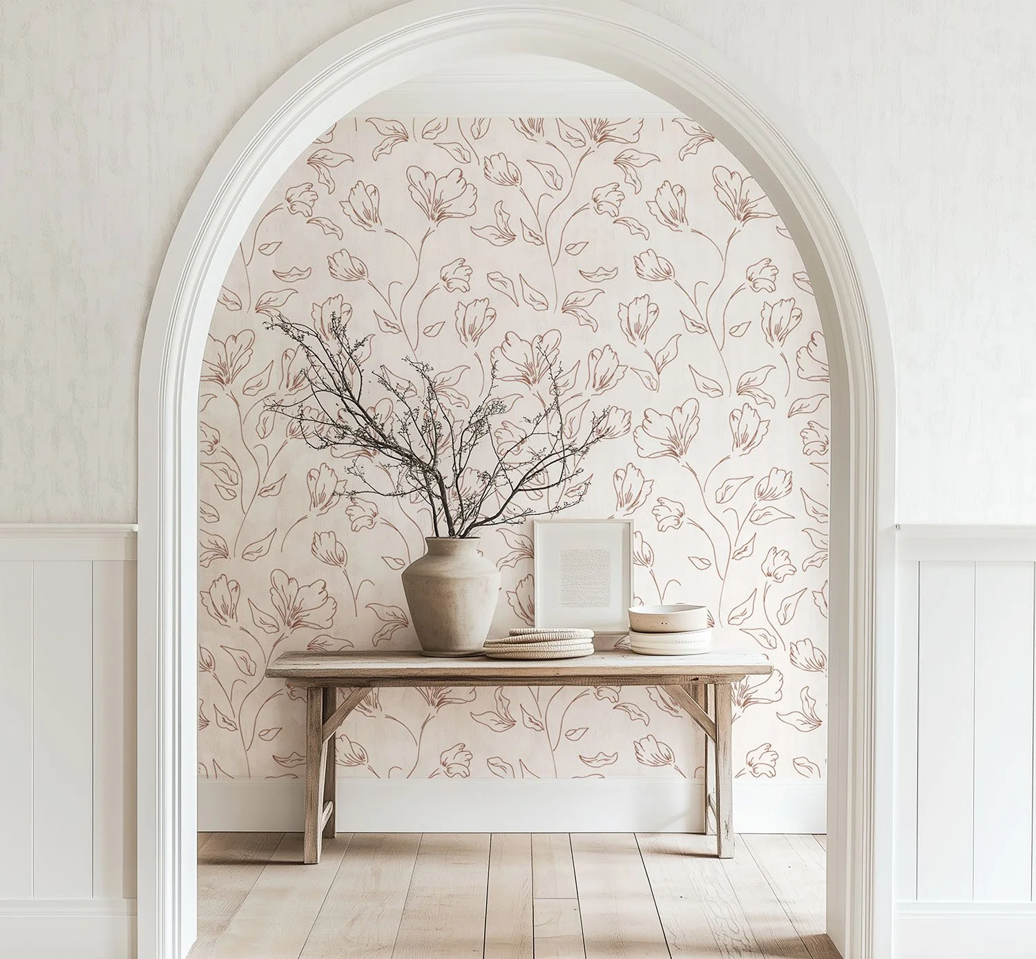 white archway in front of tableau of neutral table, with natural accessories, vase with branches, in front of wallpaper background