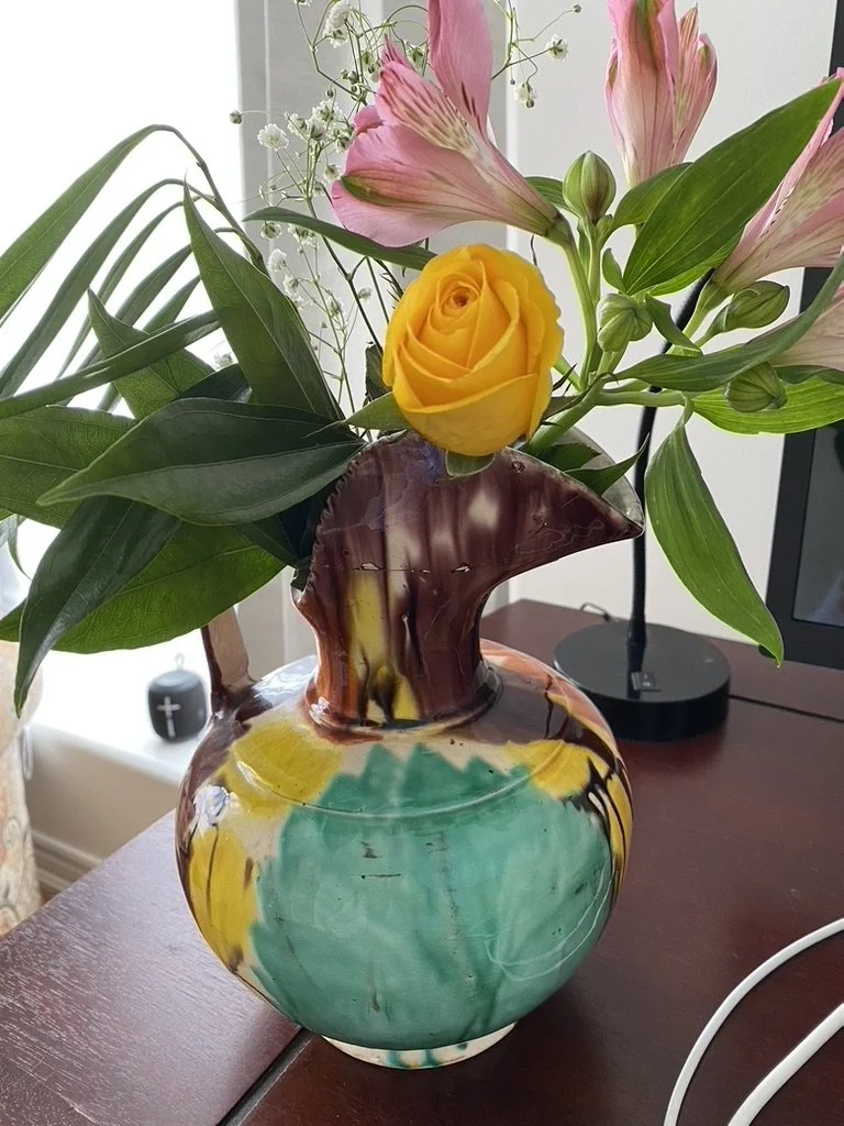 minimalist flowers and foliage in a colourful pottery vase
