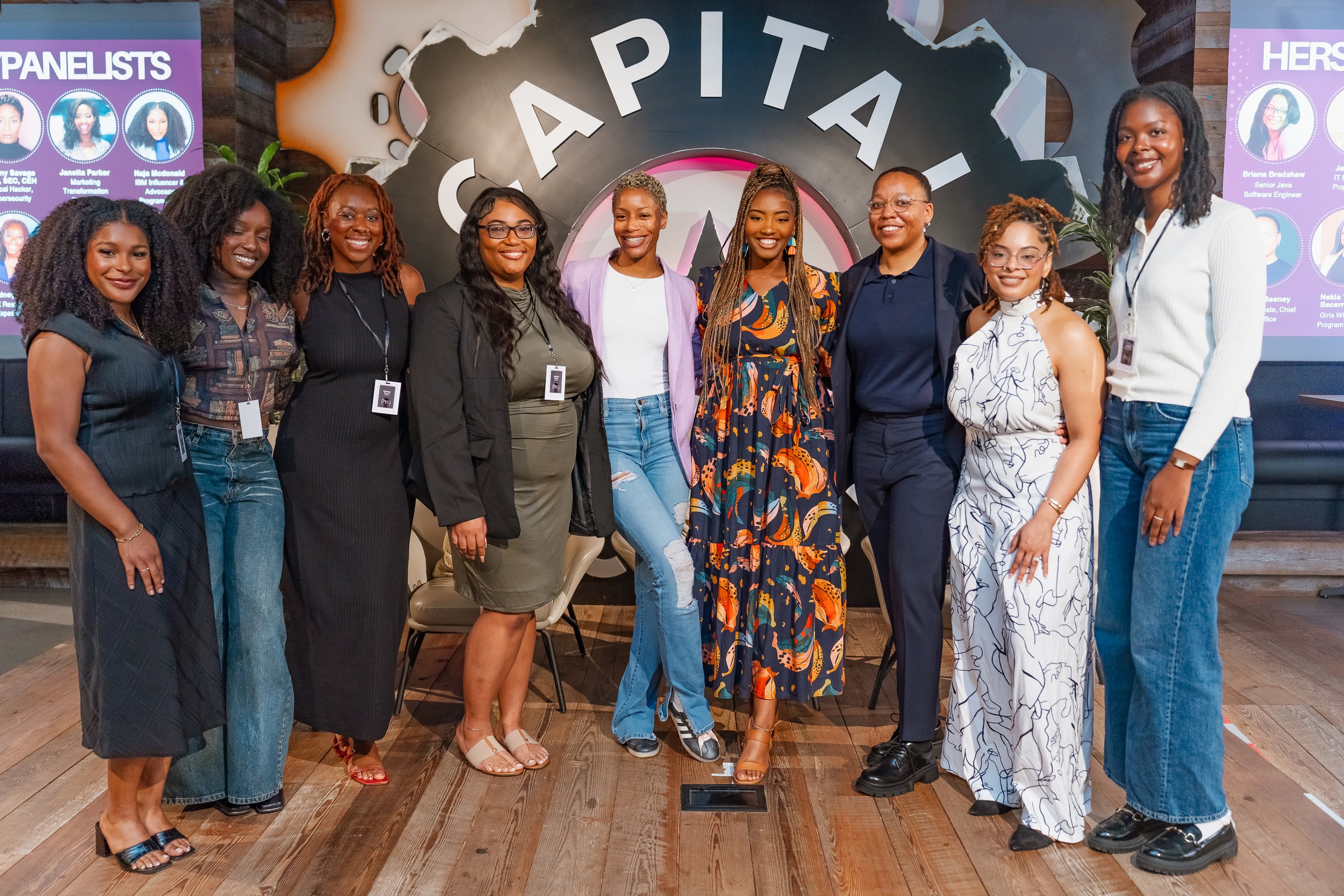 Group of young women posing, smiling, and making hand signs in a gathering indoors.