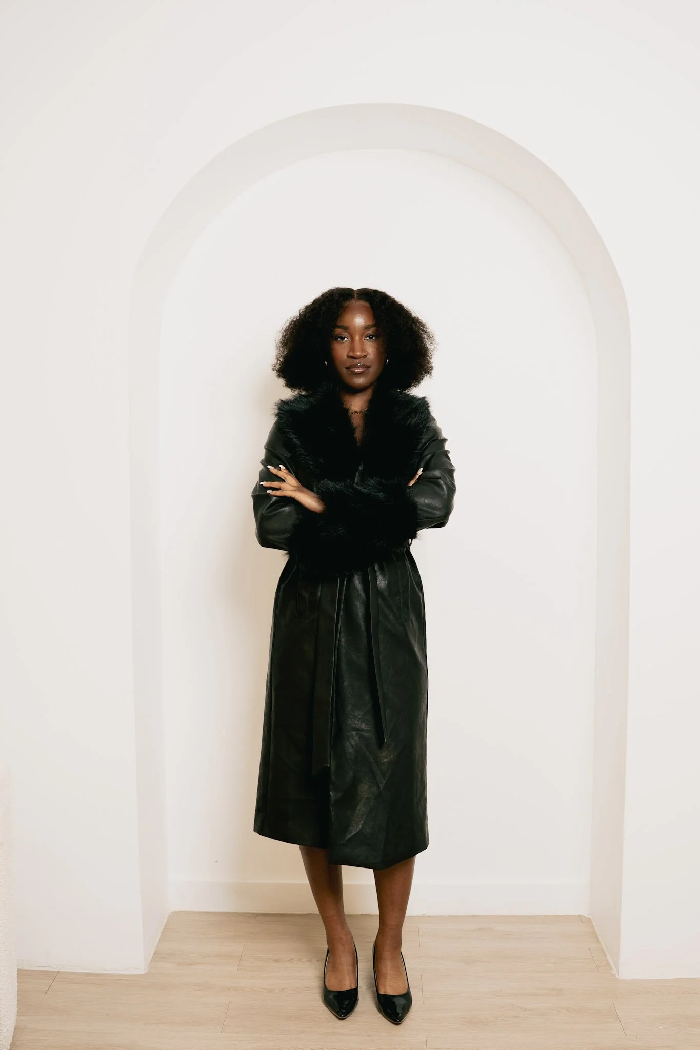 Woman with braids wearing a white shirt and brown top against a neutral indoor background.