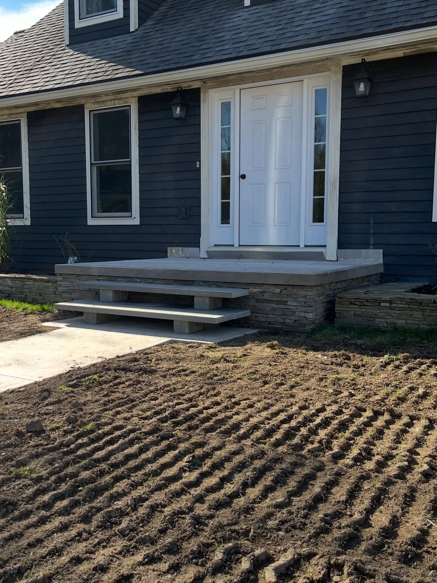 For the final phase of this three-part porch project, we installed stone veneer on the block foundation to match the style of the adjacent hardscape walls. With the homeowner&rsquo;s help, each stone was individually cut for a precise fit. We complet