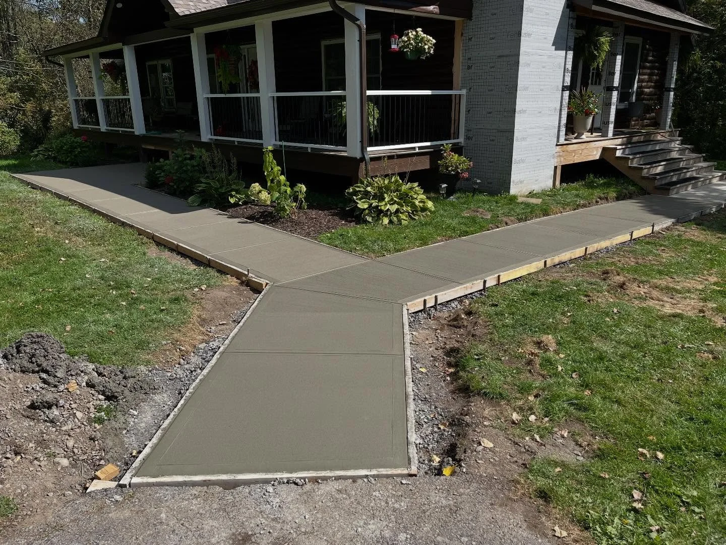 This homeowner wanted a double-entry sidewalk from the driveway along with a front porch stair pad. We designed a split Y layout, excavated the area, installed and compacted a crusher-run base, formed the concrete with steel reinforcement, and finish