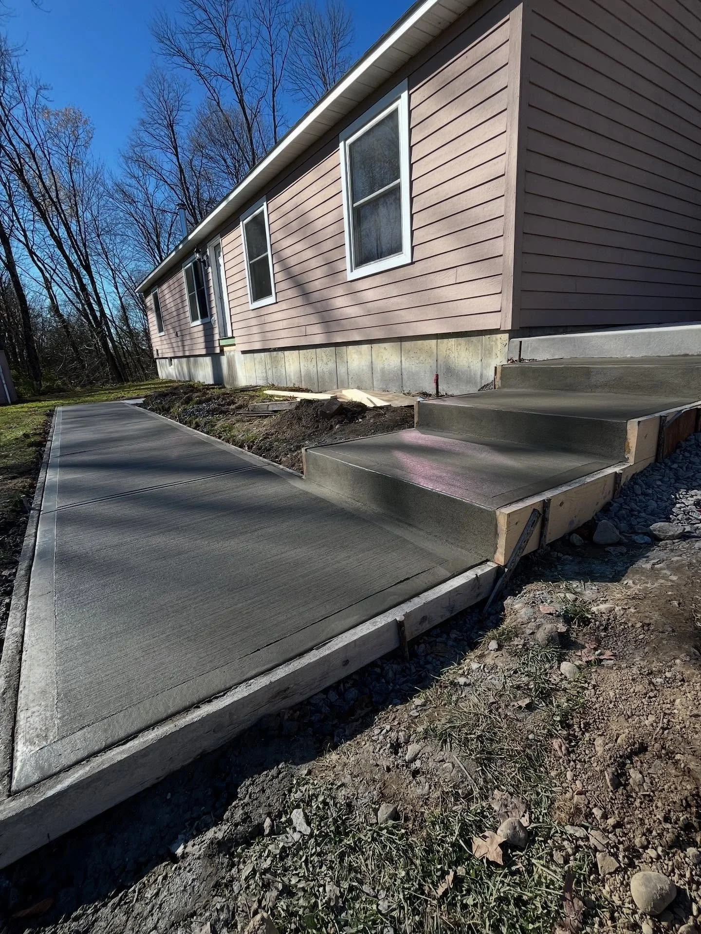 Phase two of this project included installing a set of concrete steps and a connecting walkway from the home&rsquo;s front entryway to the garage and side entrance. Constructing concrete steps requires additional attention to detail, including removi