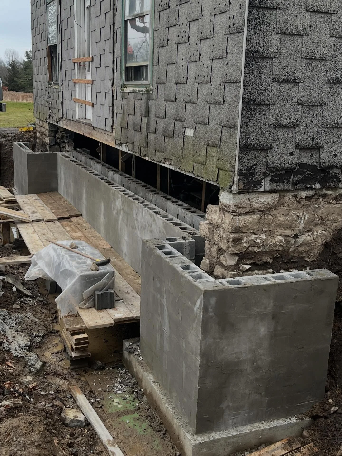 Part two of the foundation restoration project involved constructing interior and exterior concrete block piers at the corners of the remaining stone foundation. These piers will allow the corners to be fully encased in concrete, preventing further d