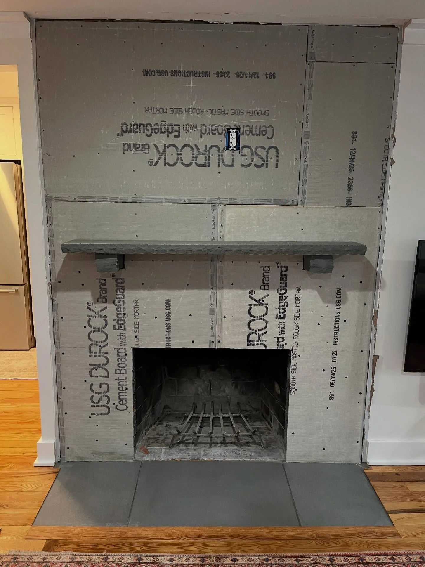 We transformed this previously shiplap-trimmed fireplace into a natural stone centerpiece. The project began with removing the wood trim and using a chipping hammer to break up the existing brick hearth. We then braced and installed a bluestone mante