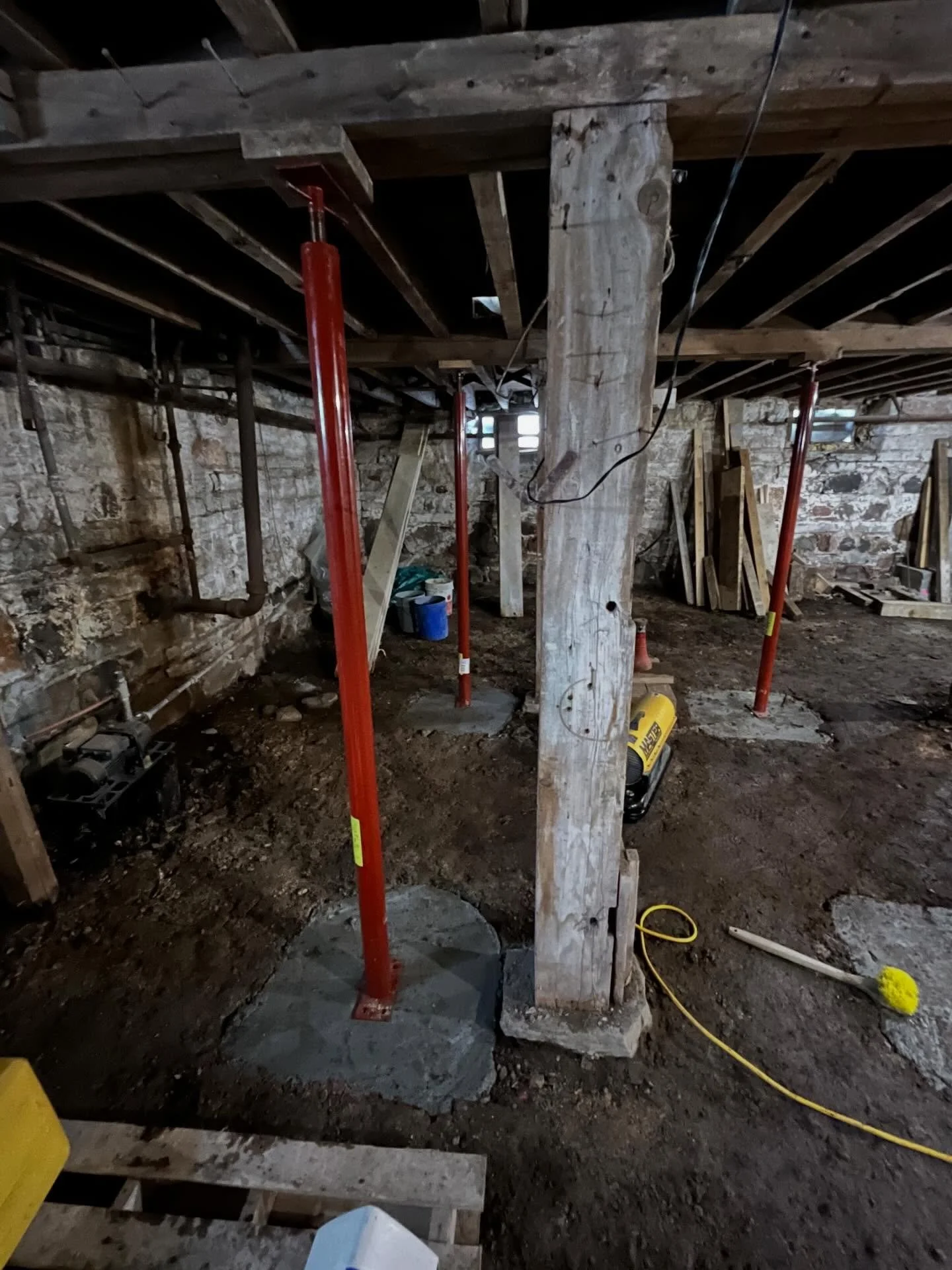 Adding structural support during the renovation of an older home is essential for long-term stability. In this farmhouse, we dug, reinforced, and poured post pads to support the main beams at the center of the home, then installed new steel columns t