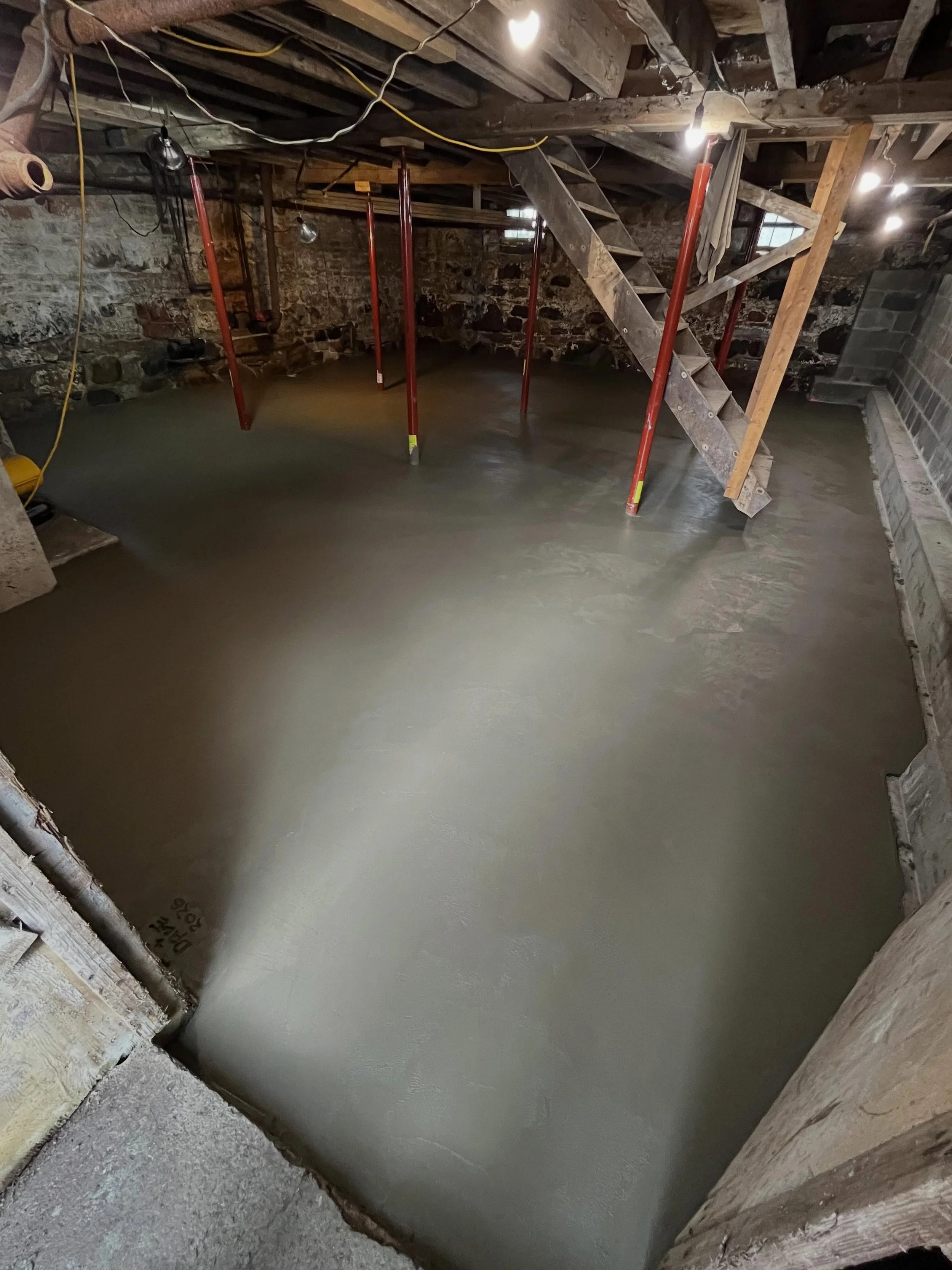 Many older home cellars have dirt floors, making the space less practical for storage. For this project, we installed a vapor barrier, steel mesh reinforcement, and expansion joints prior to the pour. Due to limited truck access, the concrete was tra