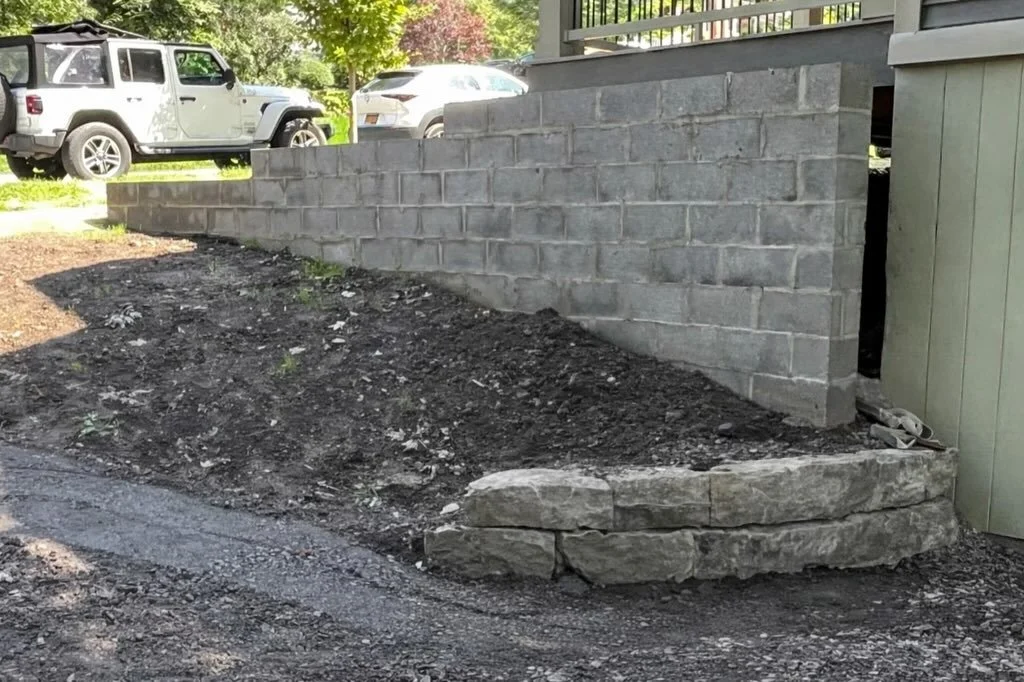 Part one of a two-phase retaining wall project designed to level the front yard of a home built on a sloped grade. We began by removing the existing retaining wall, then excavated and poured a reinforced footer. From there, we constructed a tiered ce