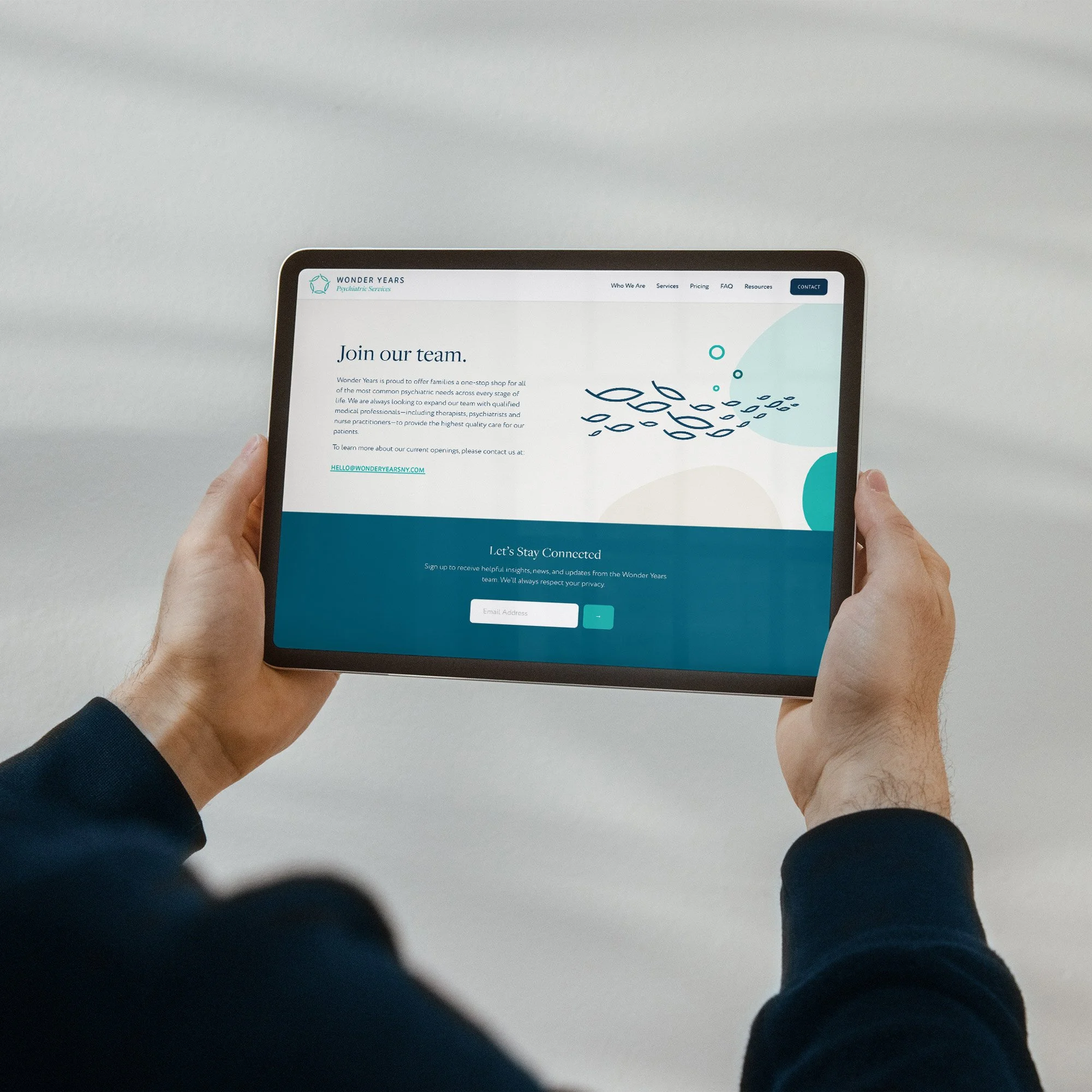 Person holding a tablet showing a website titled "Join our team" with aquatic-themed graphics and a sign-up form for updates.