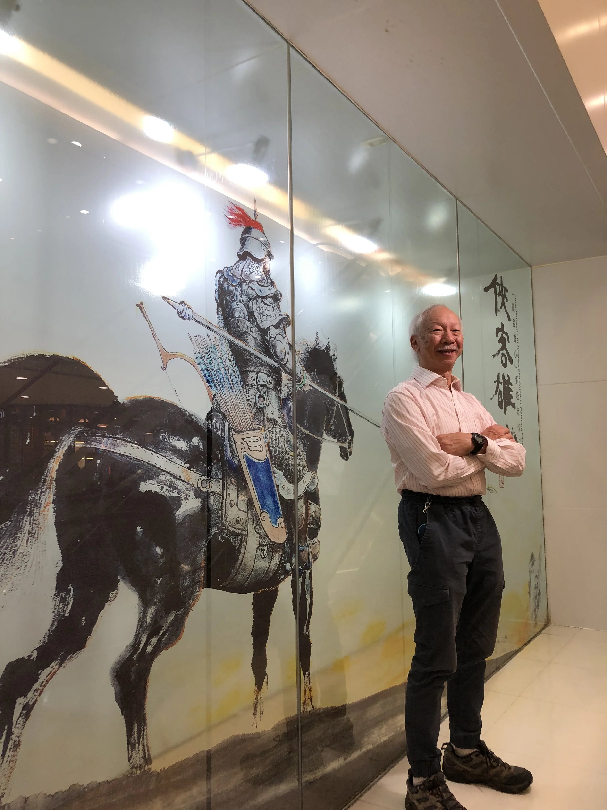 Tung Pui Sun posing in front of his painting in Hong Kong
董培新攝於香港，身後為其畫作。