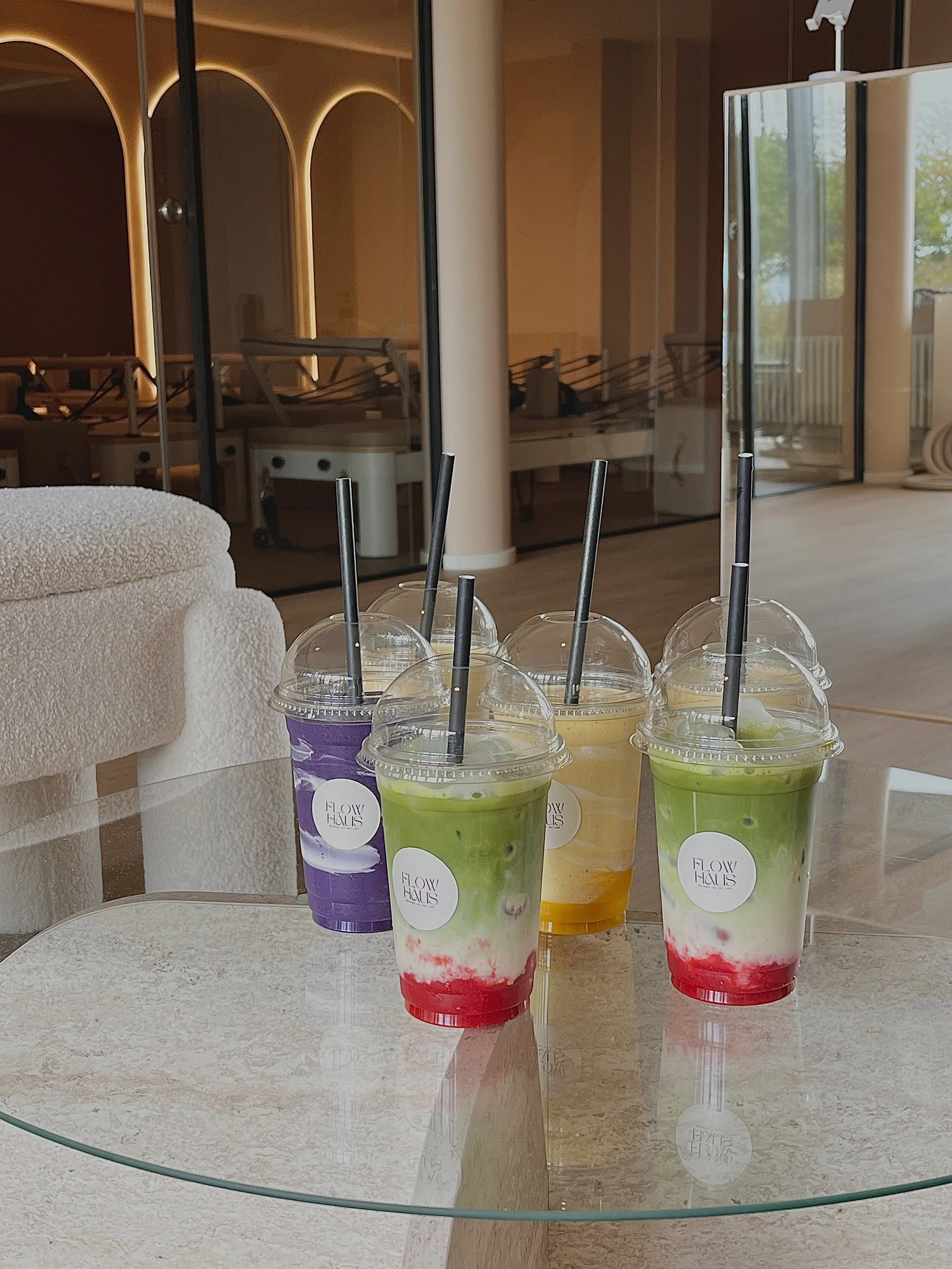 Four smoothies and matchas on a glass table