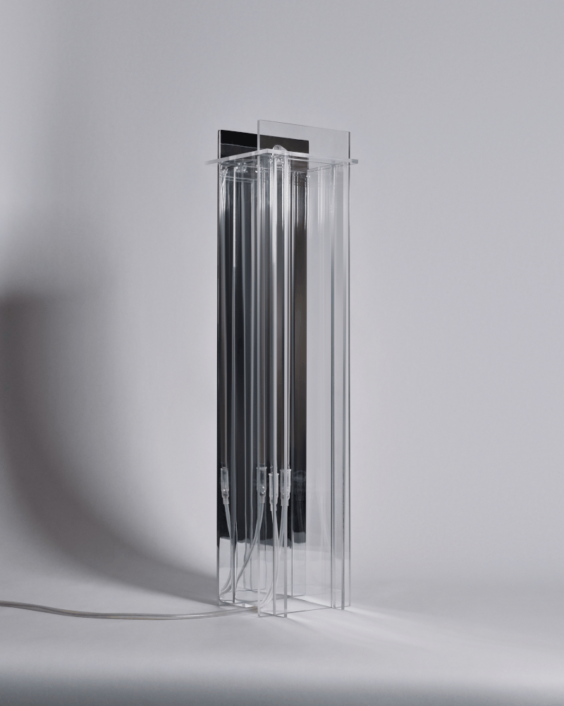 A tall, clear acrylic or glass display stand with multiple vertical slots, placed on a white surface against a light gray background.